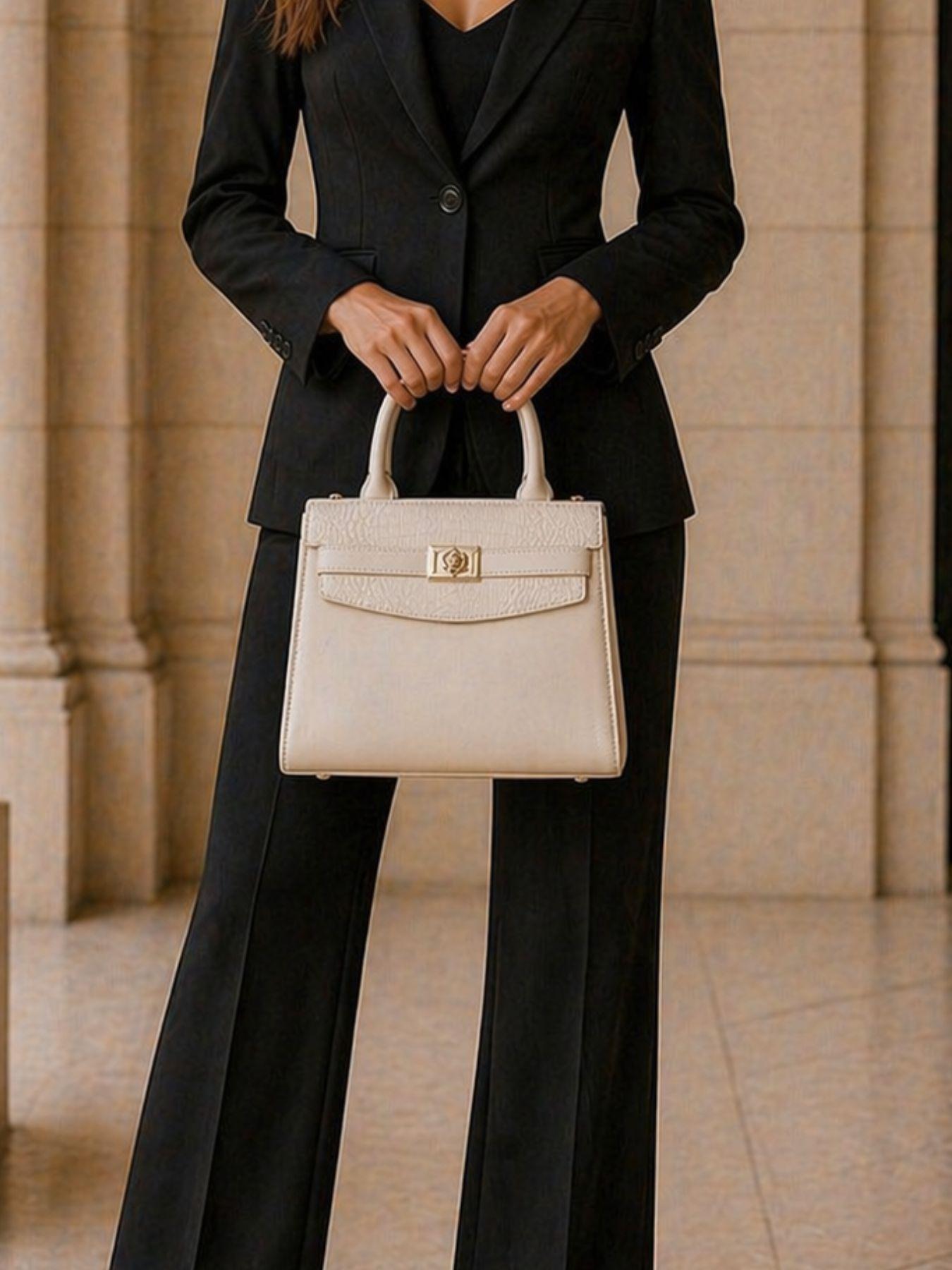 Person wearing a black suit holding a beige handbag in an indoor setting.