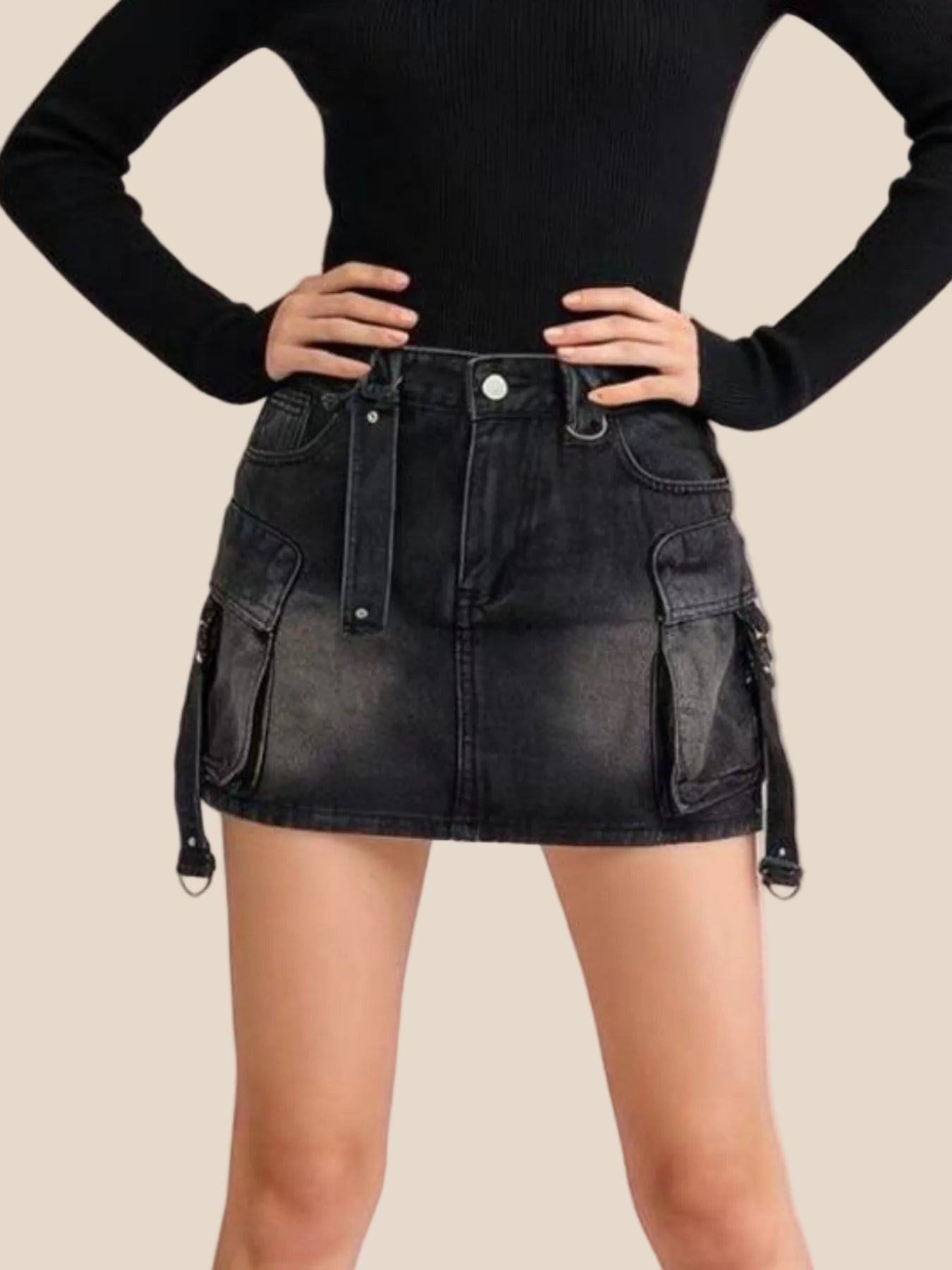 Person wearing a black denim skirt with cargo pockets on a pink background