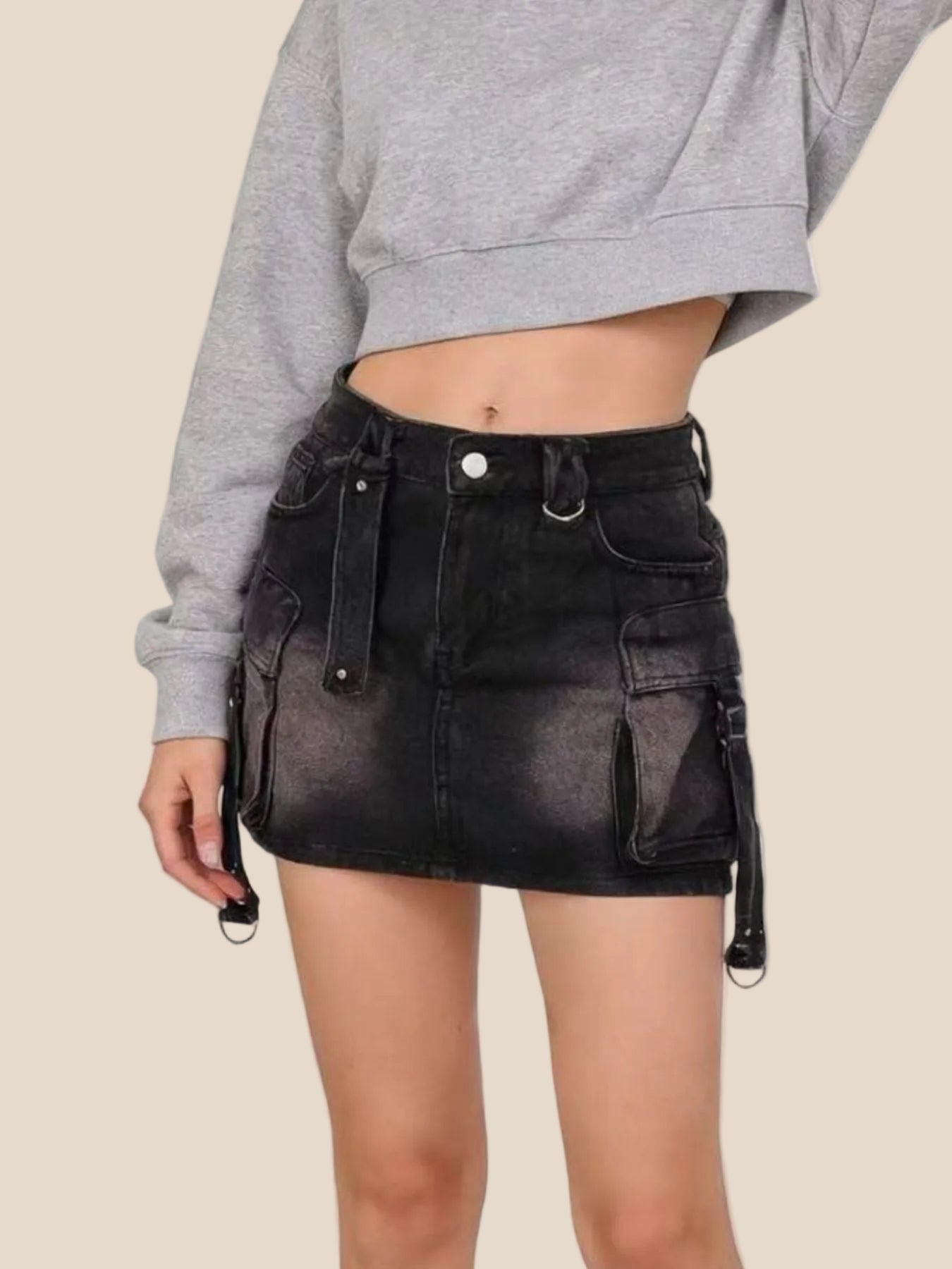 Person wearing a black denim skirt with suspenders on a plain background