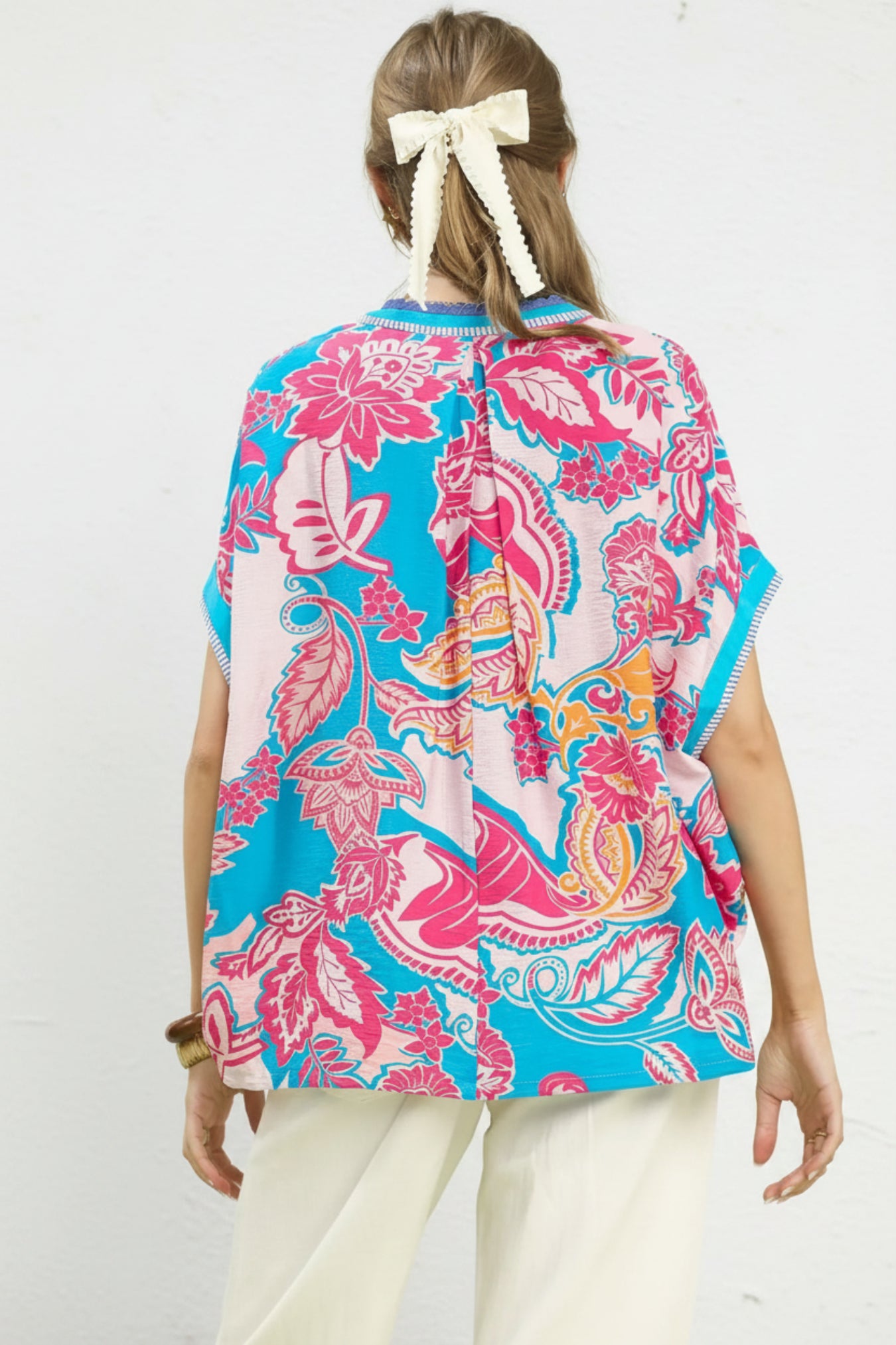 Woman wearing a colorful patterned shirt with a white background