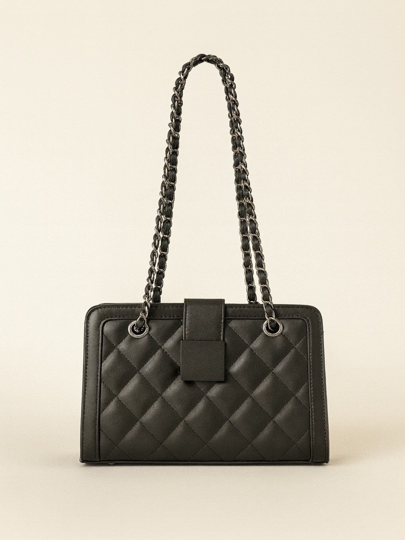 Black quilted handbag with chain strap on a beige background