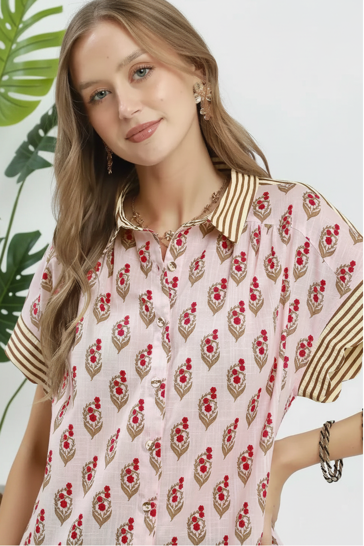 Woman wearing a pink and red patterned top with gold accents on a white background with leaves