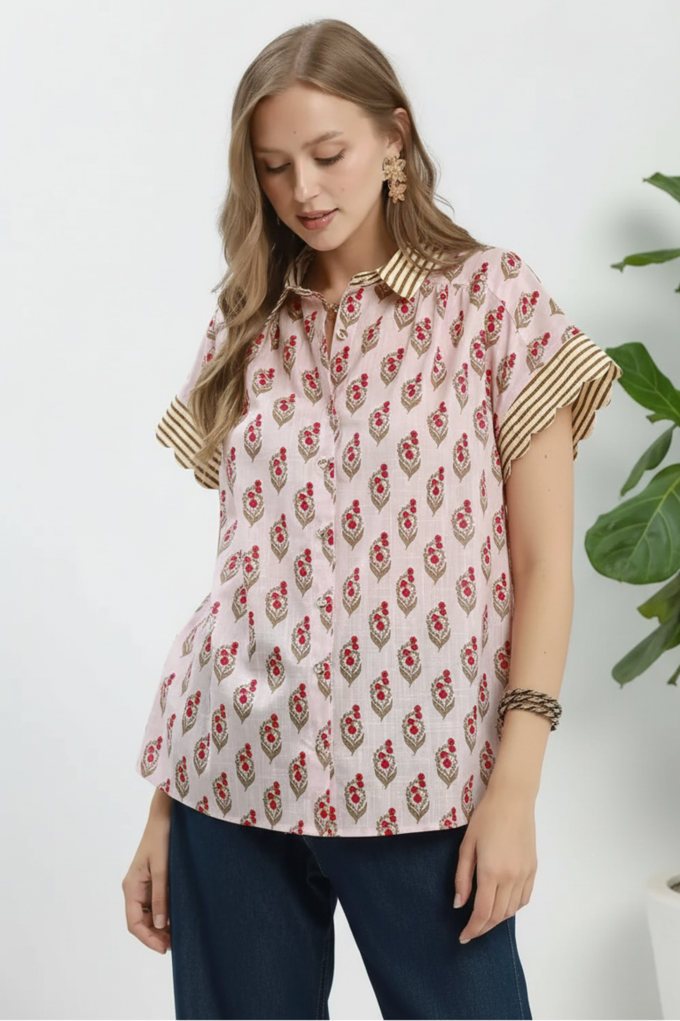 Woman wearing a floral blouse with gold accents on a white background