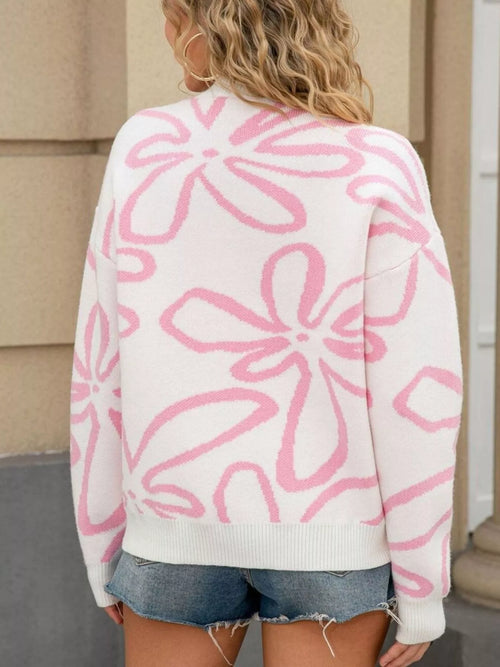 Person wearing a white sweater with pink floral patterns outdoors.