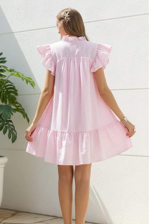 Woman wearing a pink dress against a white outdoor background