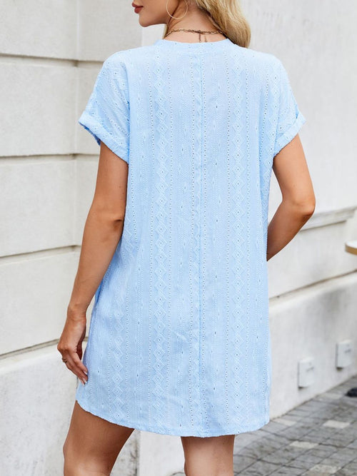 Woman wearing a light blue dress against a white wall.