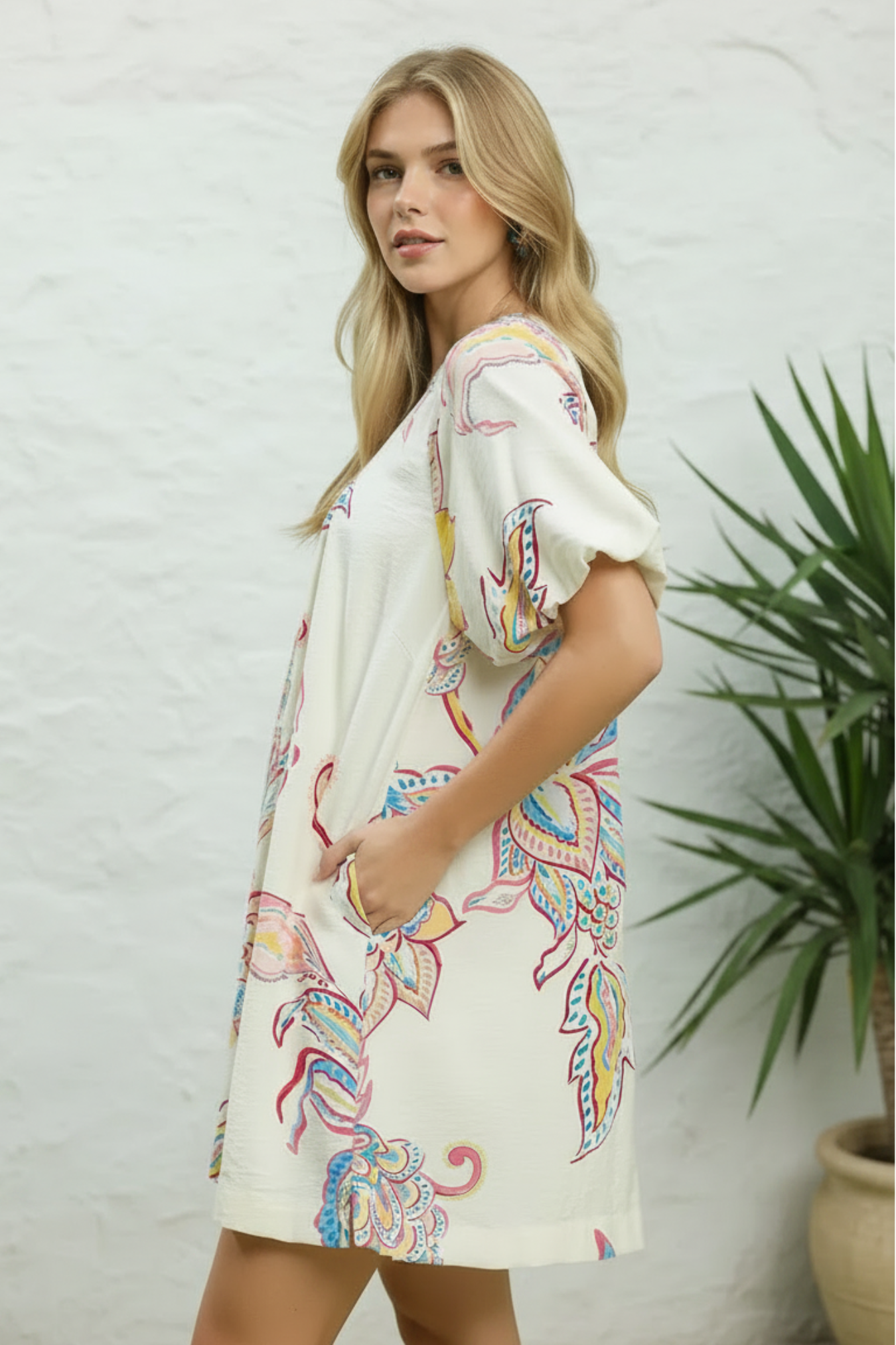 Woman wearing a colorful dress with a white background and plant
