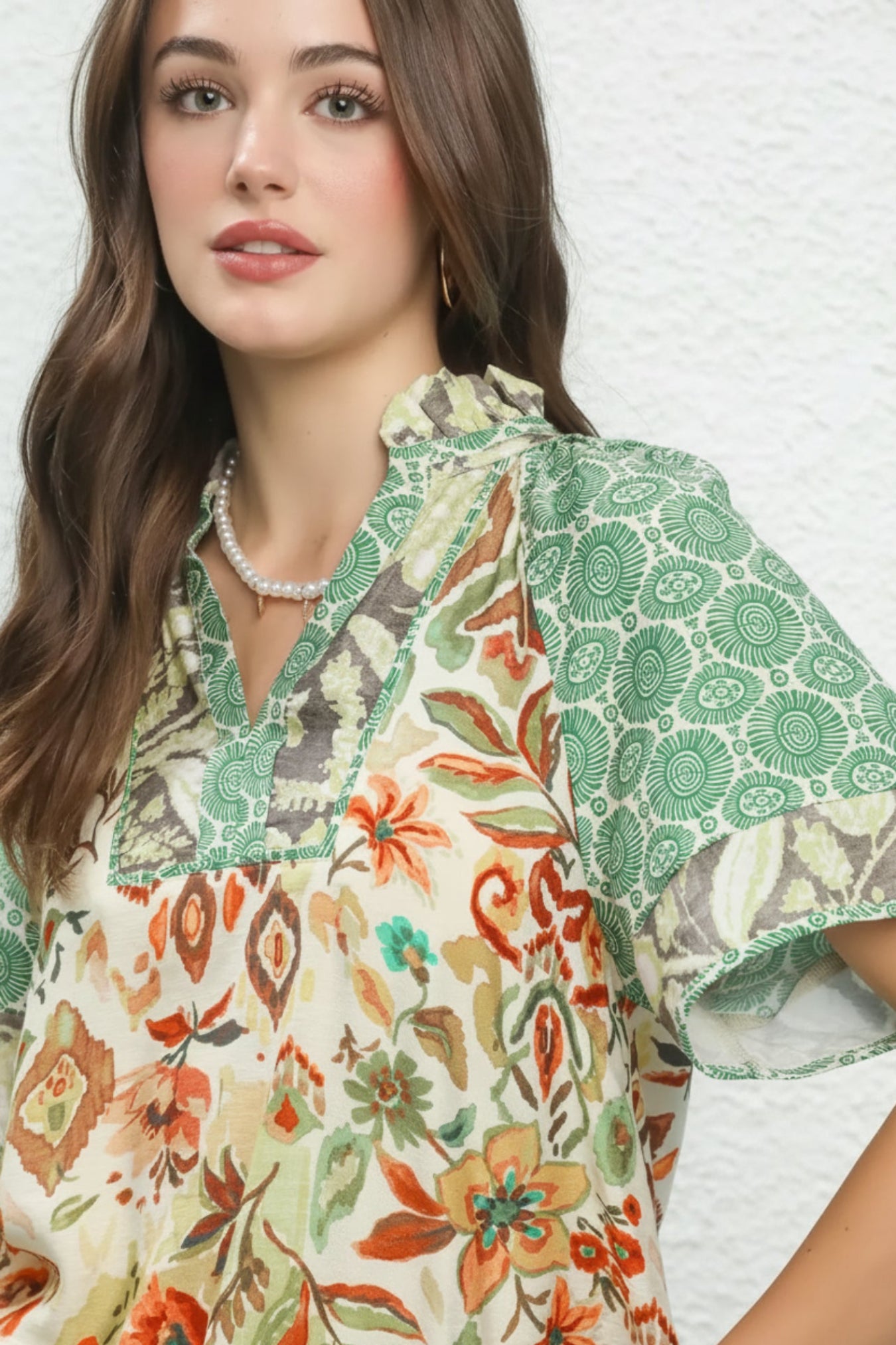 Woman wearing a floral and patterned blouse against a white background