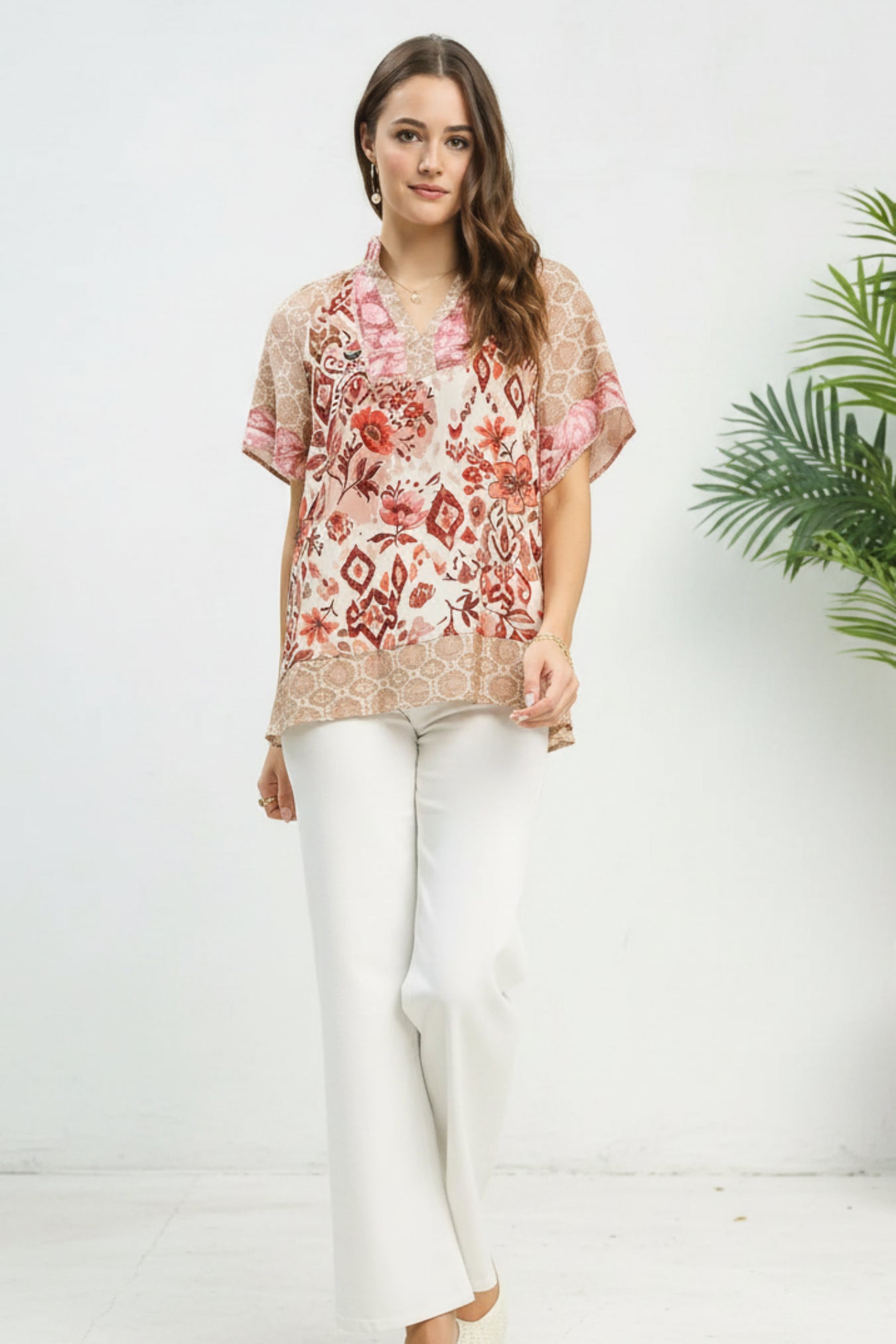 Woman wearing a floral blouse and white pants on a white background