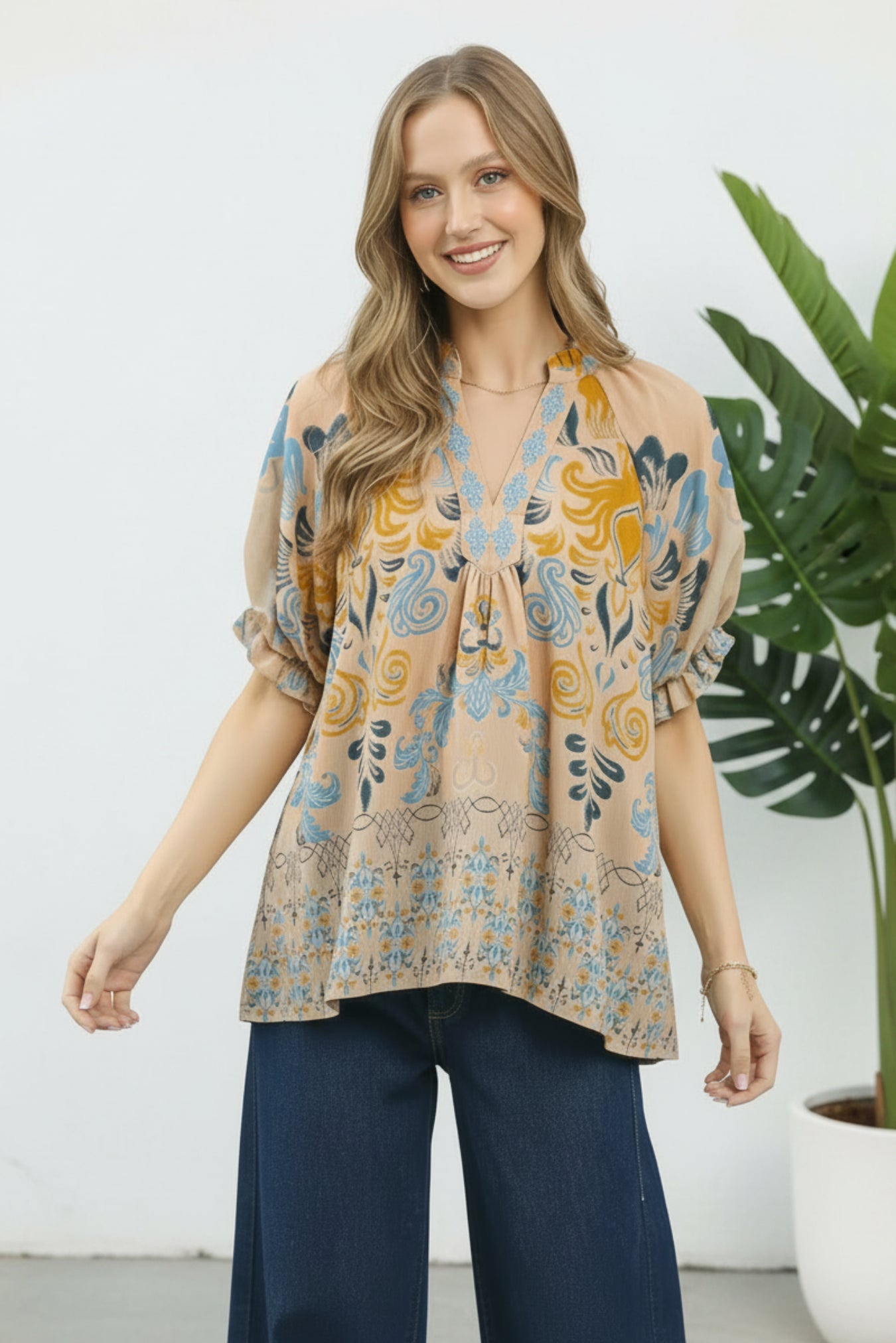 Woman wearing a patterned blouse with a plant and white background