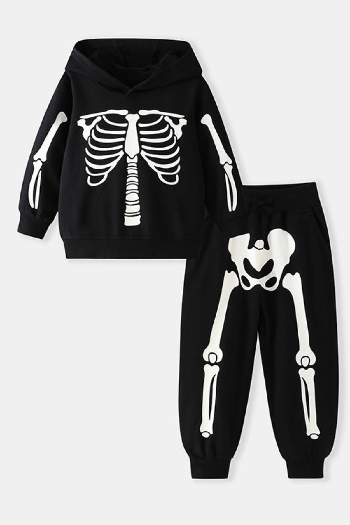 A two-piece kids' skeleton print outfit consisting of a black hoodie with a white rib cage graphic on the front and sleeves, and matching black jogger pants with a white pelvic bone and leg skeleton print, displayed on a light gray background.