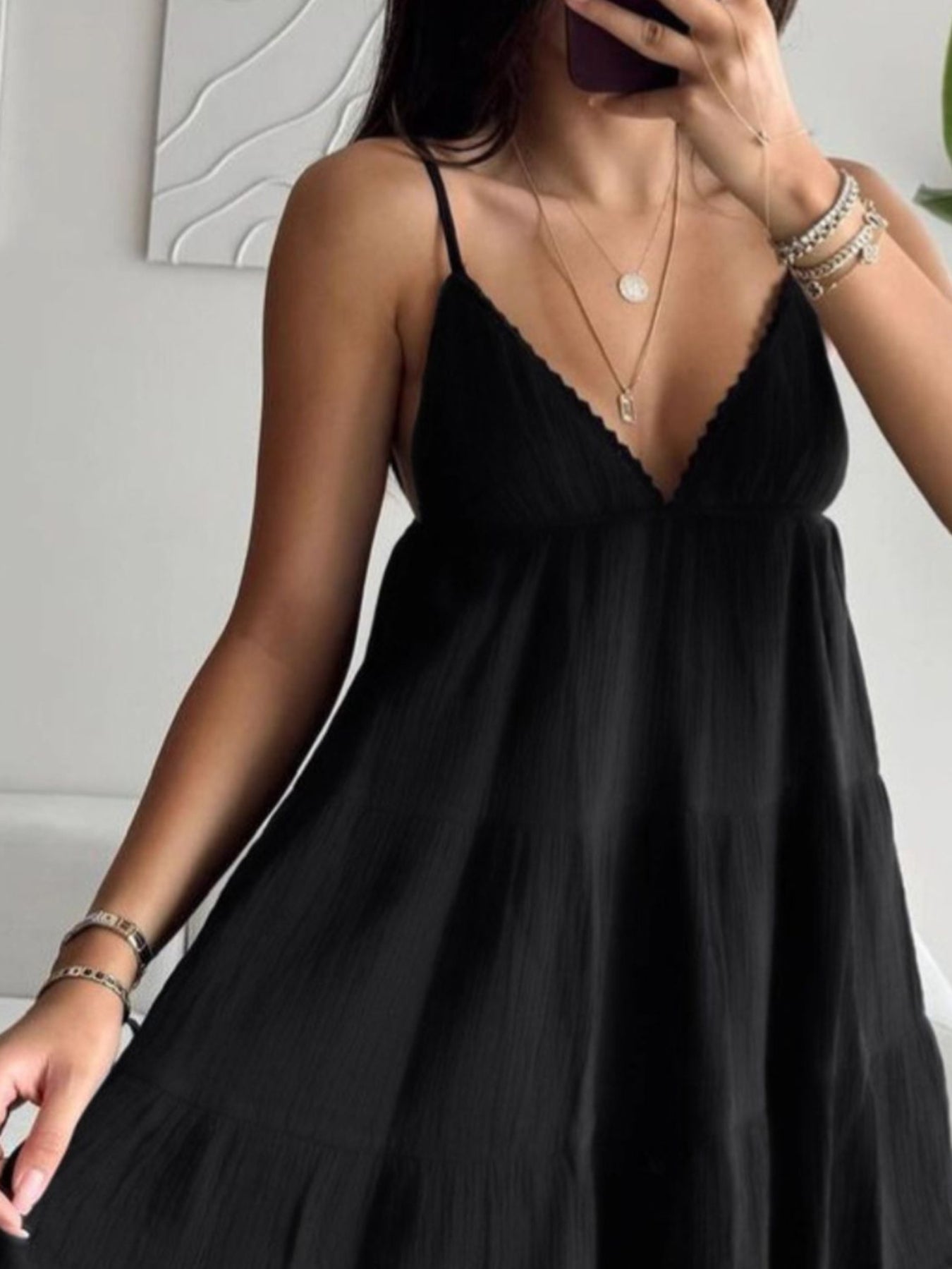 Woman wearing a black slip dress indoors with a neutral background
