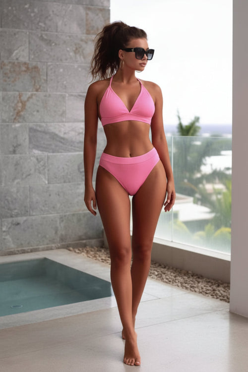 Woman wearing a pink bikini standing by a pool with a scenic view.