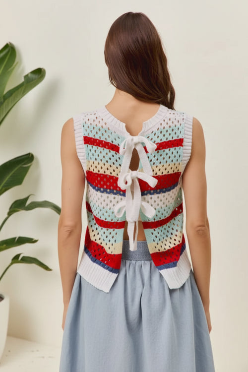 Woman wearing a colorful crochet vest with a white bow on a white background