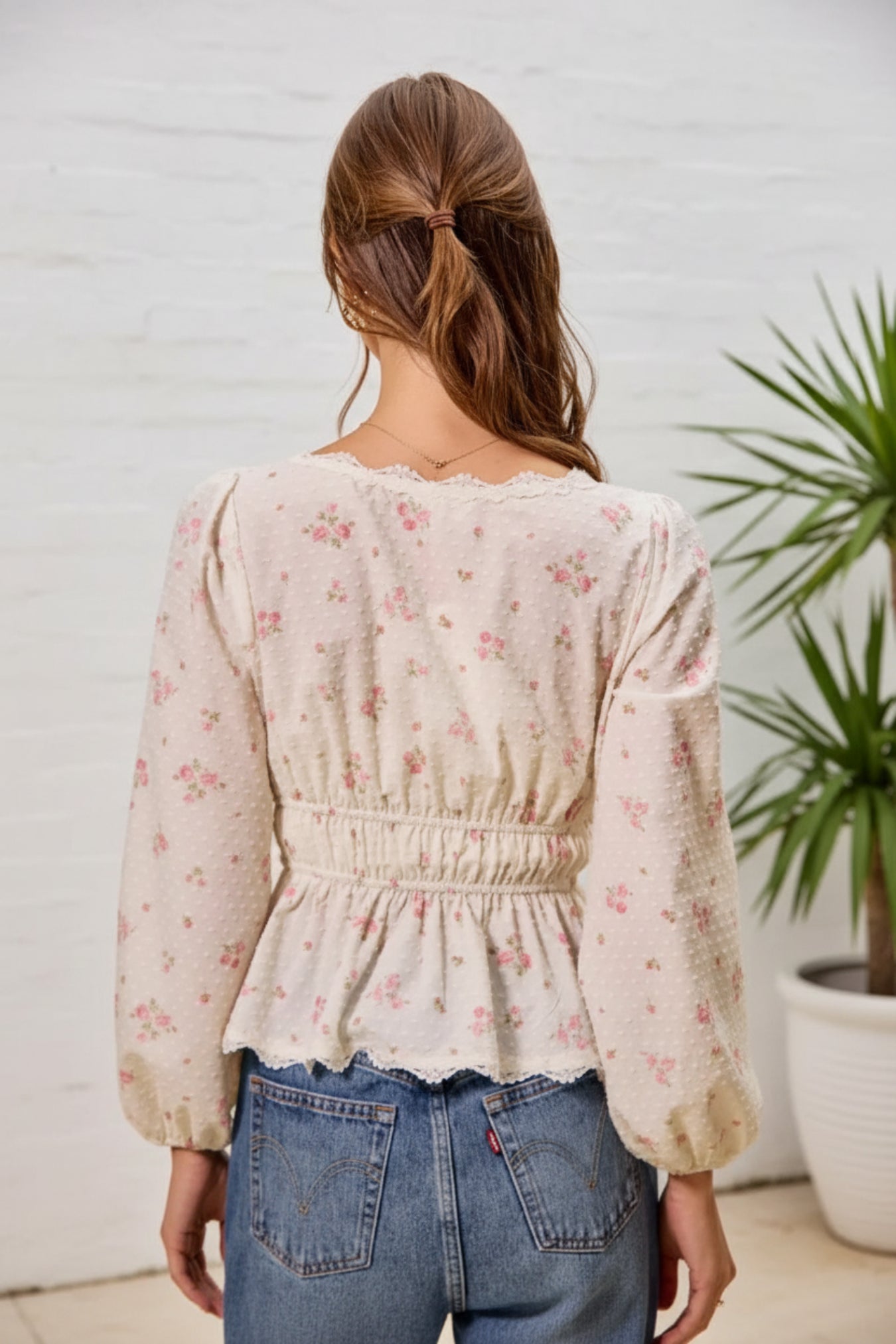 Woman wearing a floral blouse with long sleeves on a beige background