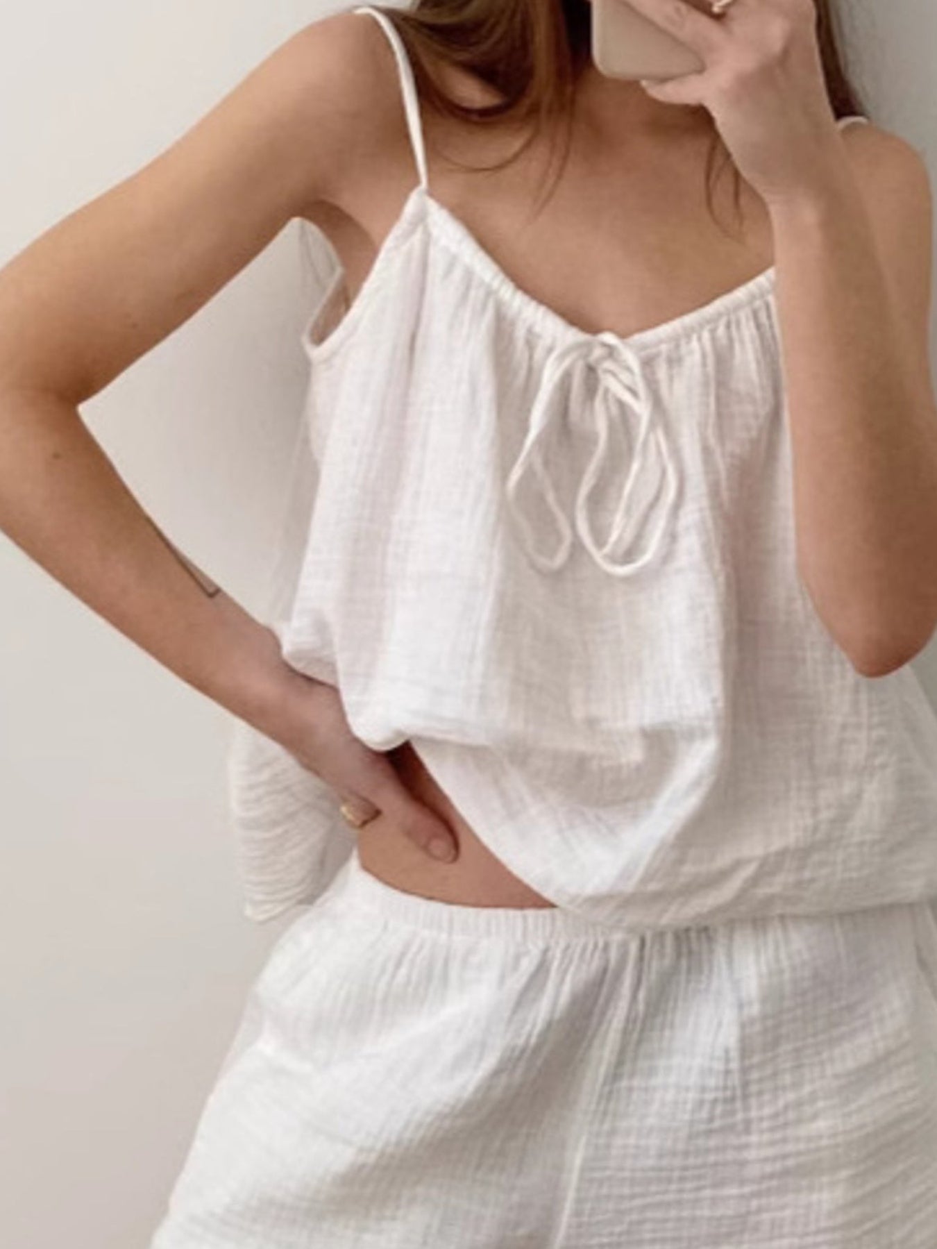 Person wearing a white sleeveless top and shorts set against a plain background