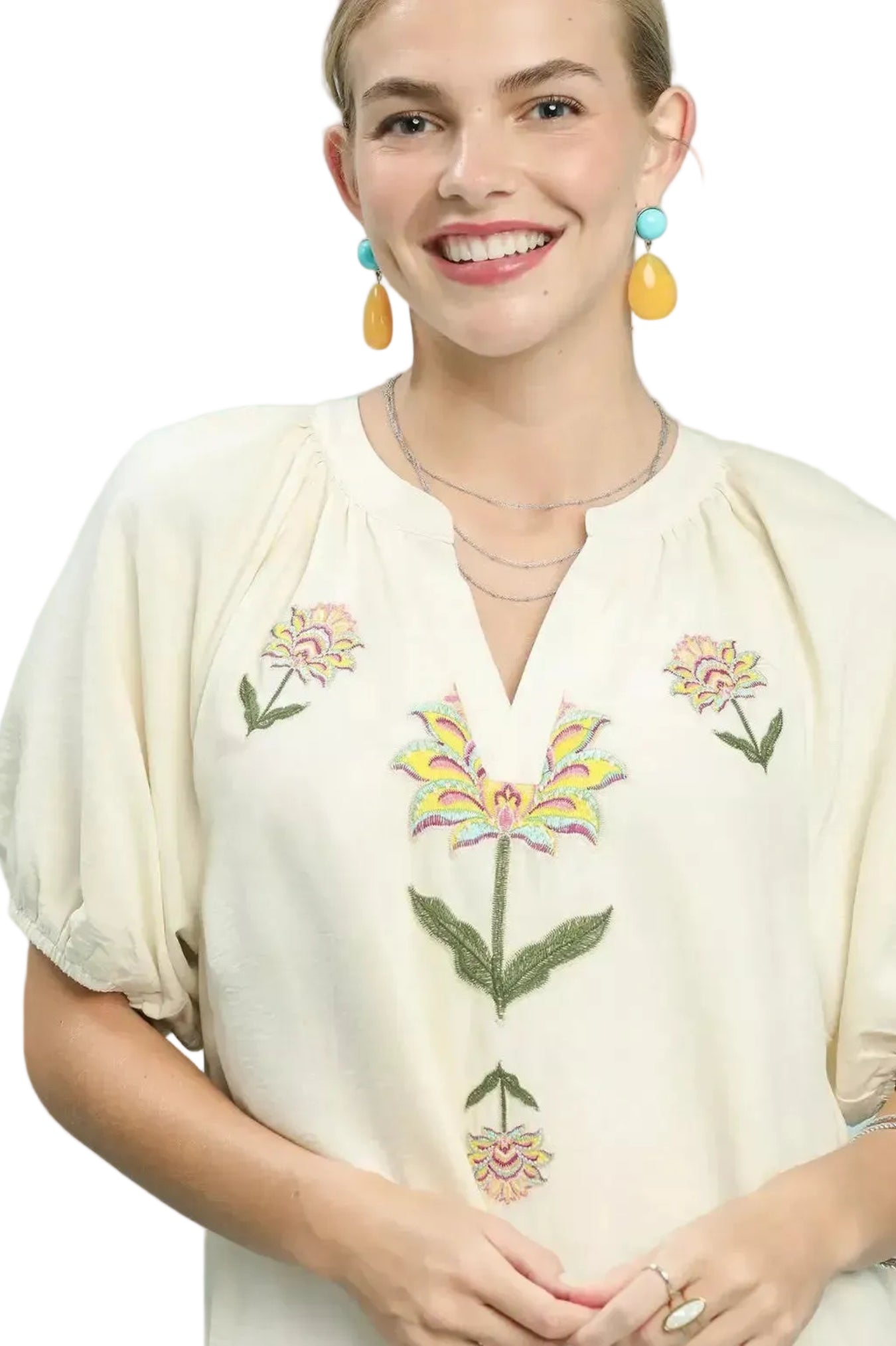 Woman wearing a cream-colored blouse with floral embroidery on a white background