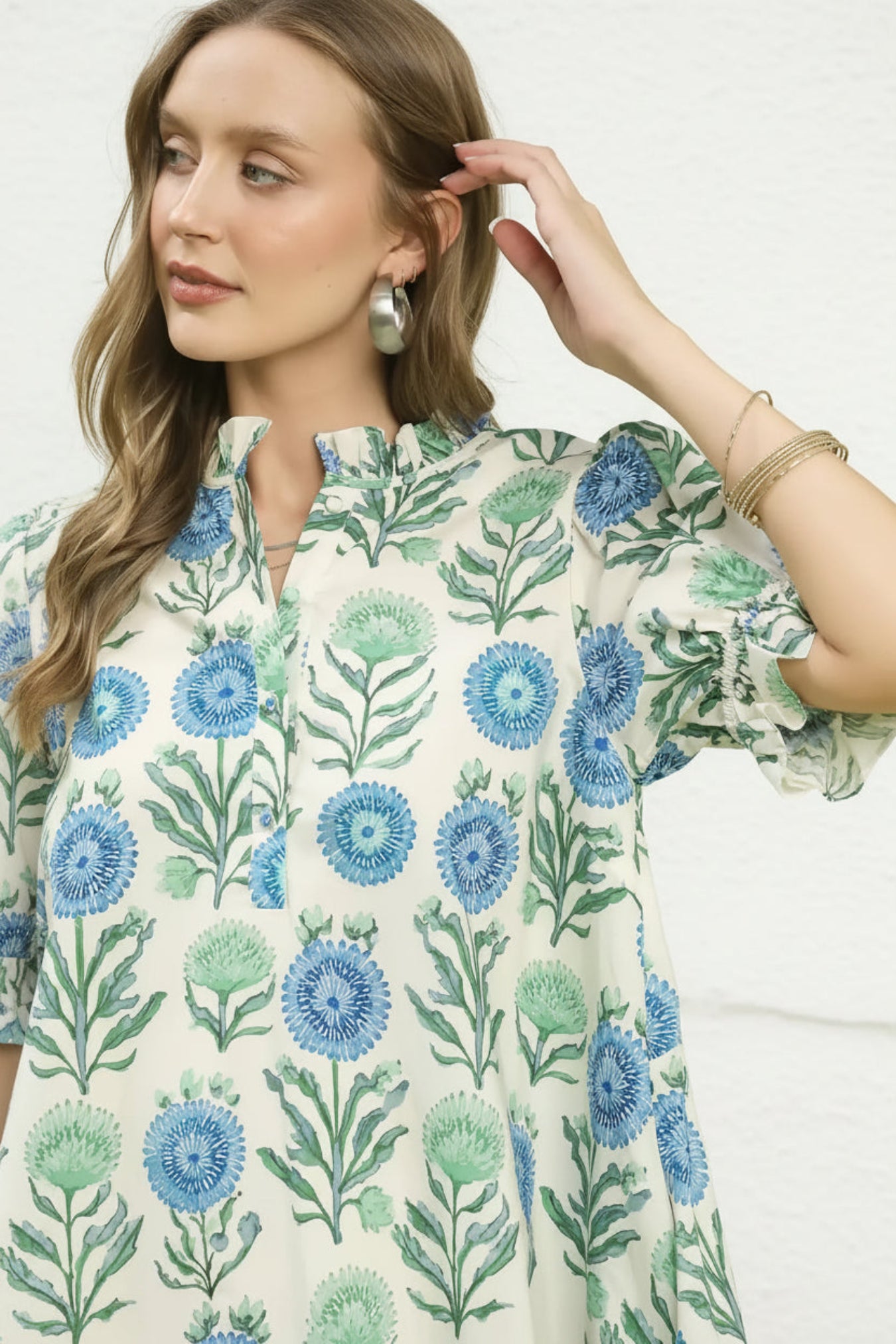 Woman wearing a floral patterned dress with blue and green flowers on a white background