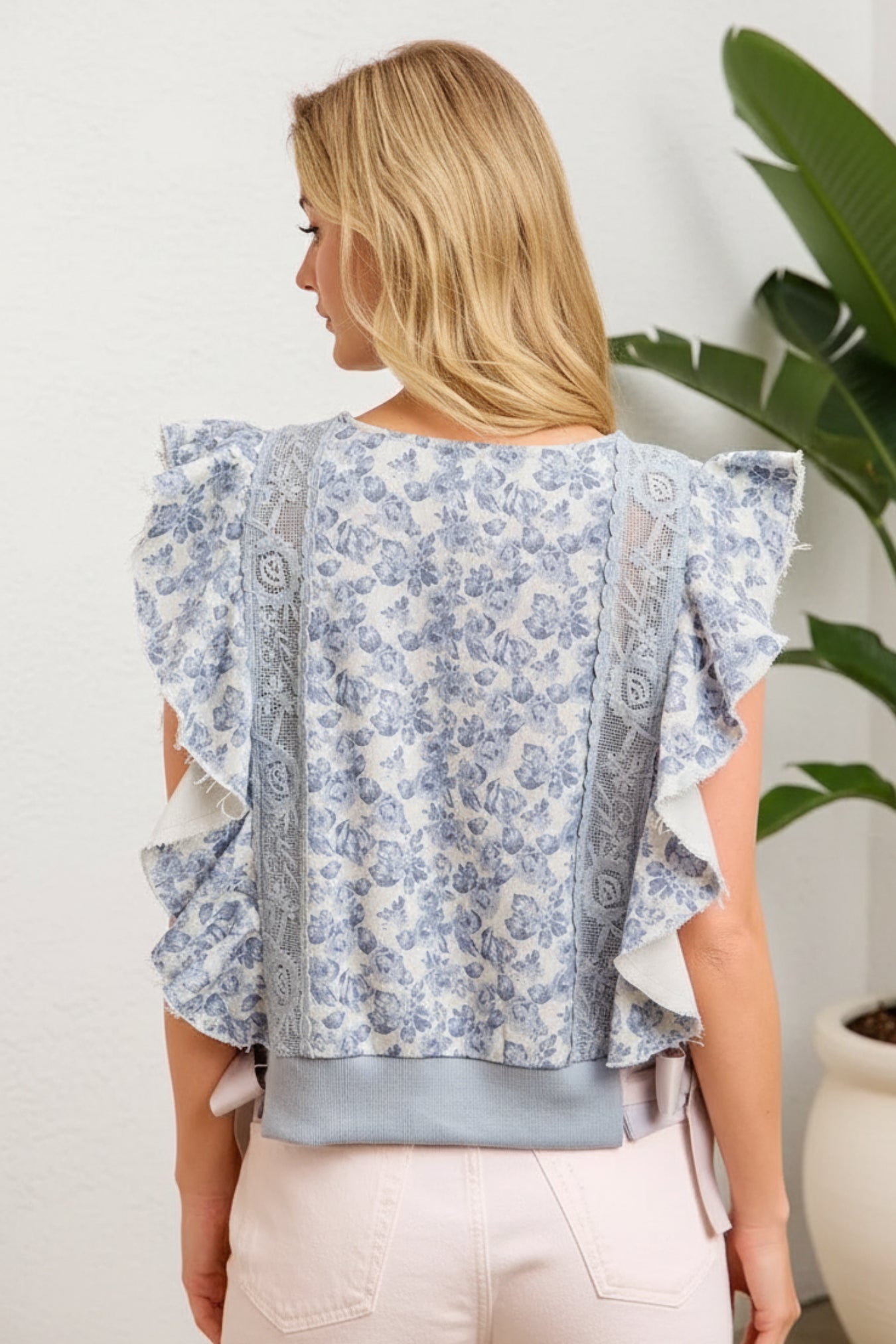 Woman wearing a floral blouse with ruffled sleeves against a white background
