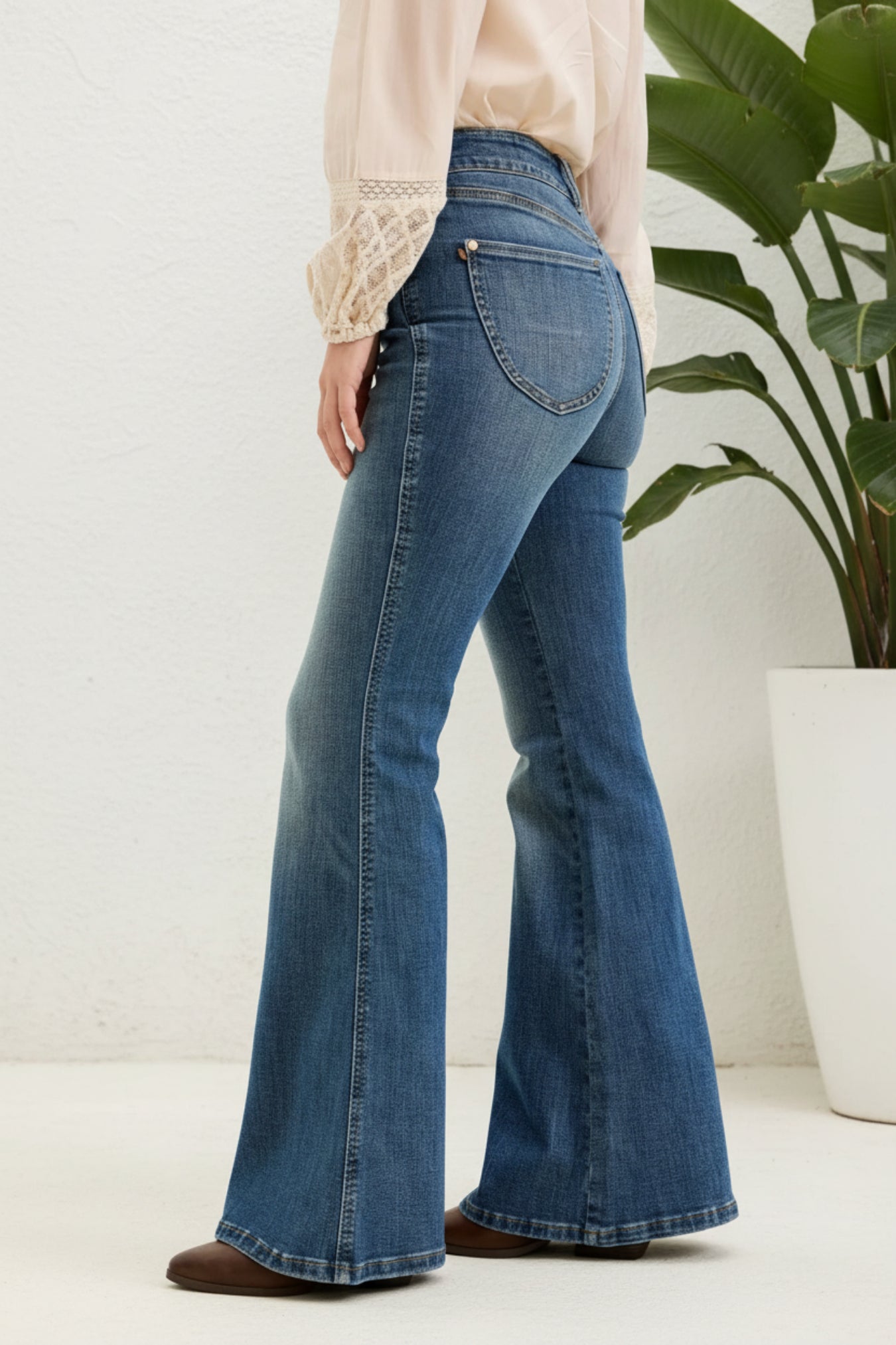 Blue flared jeans worn by a person on a white background