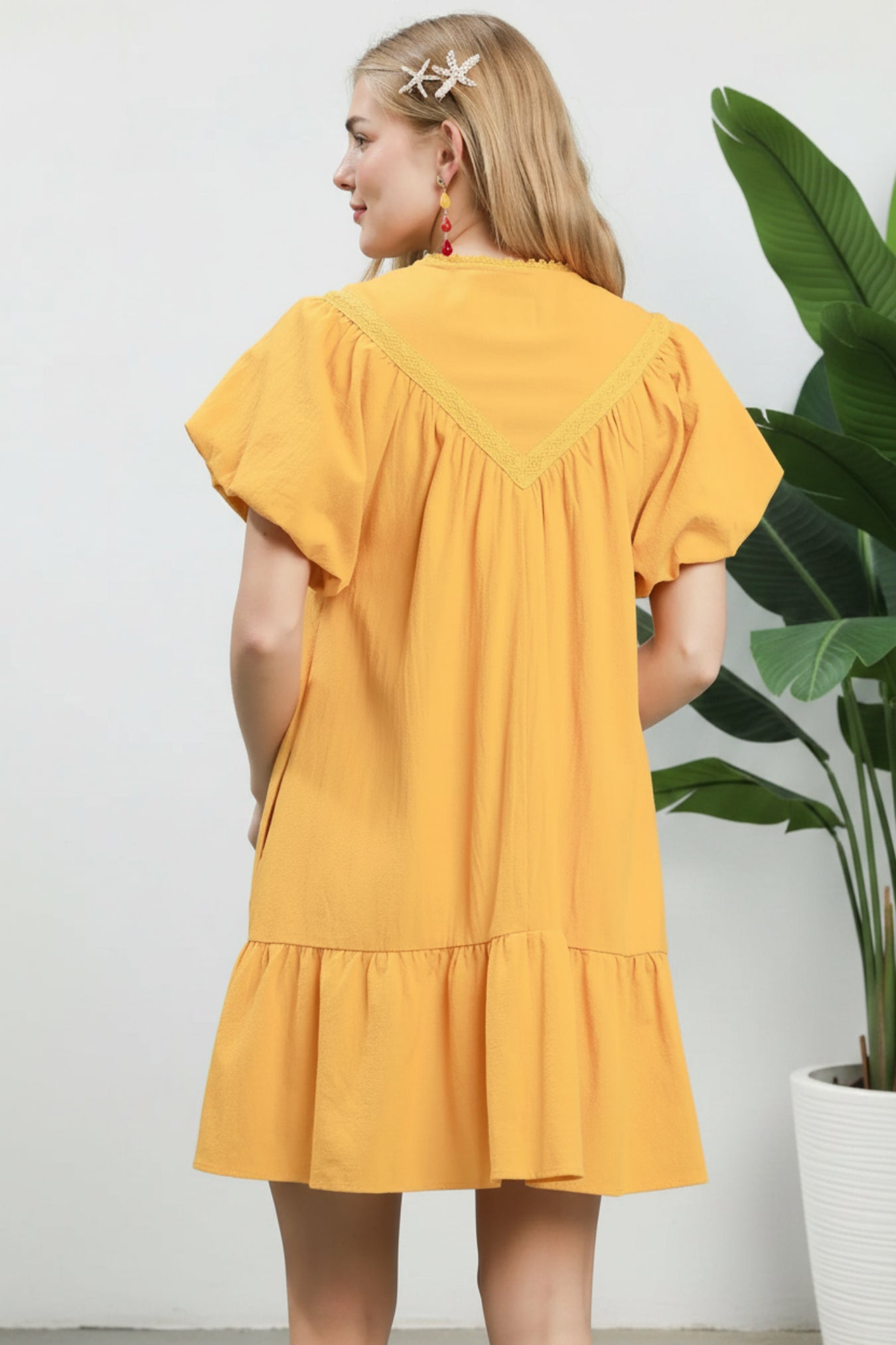 Woman wearing a yellow dress against a light blue background