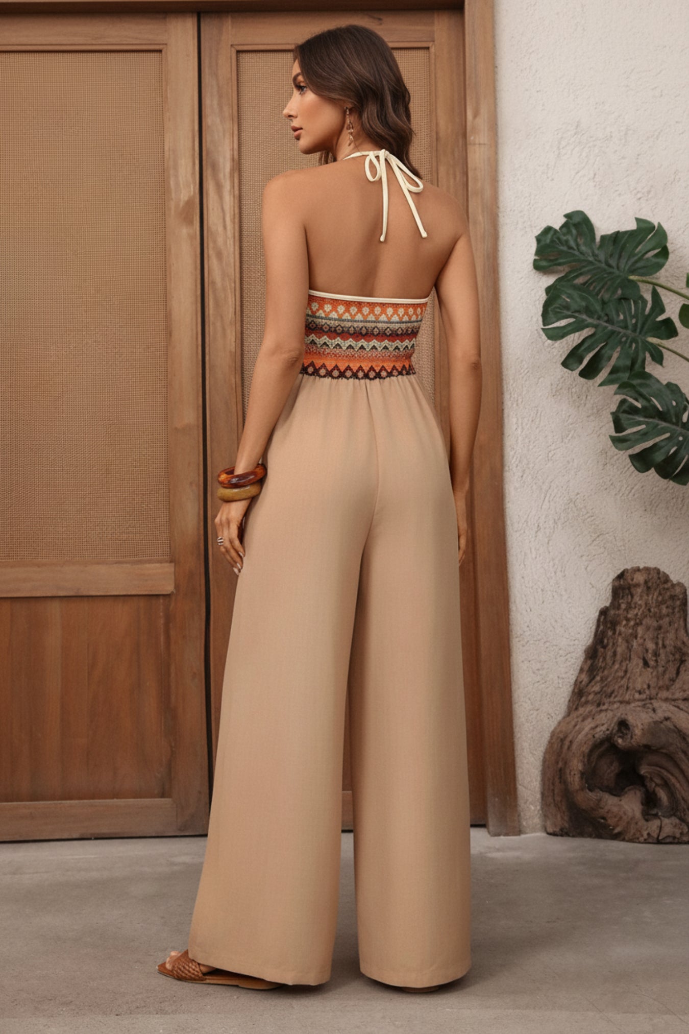 Woman wearing a beige jumpsuit with an open back in a casual setting.