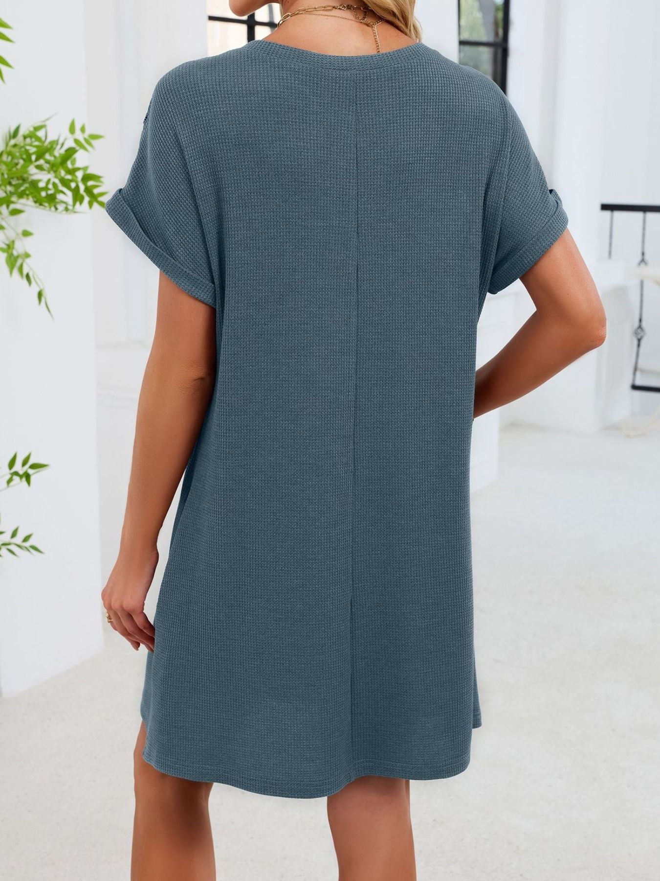 Person wearing a teal dress in a minimal indoor setting