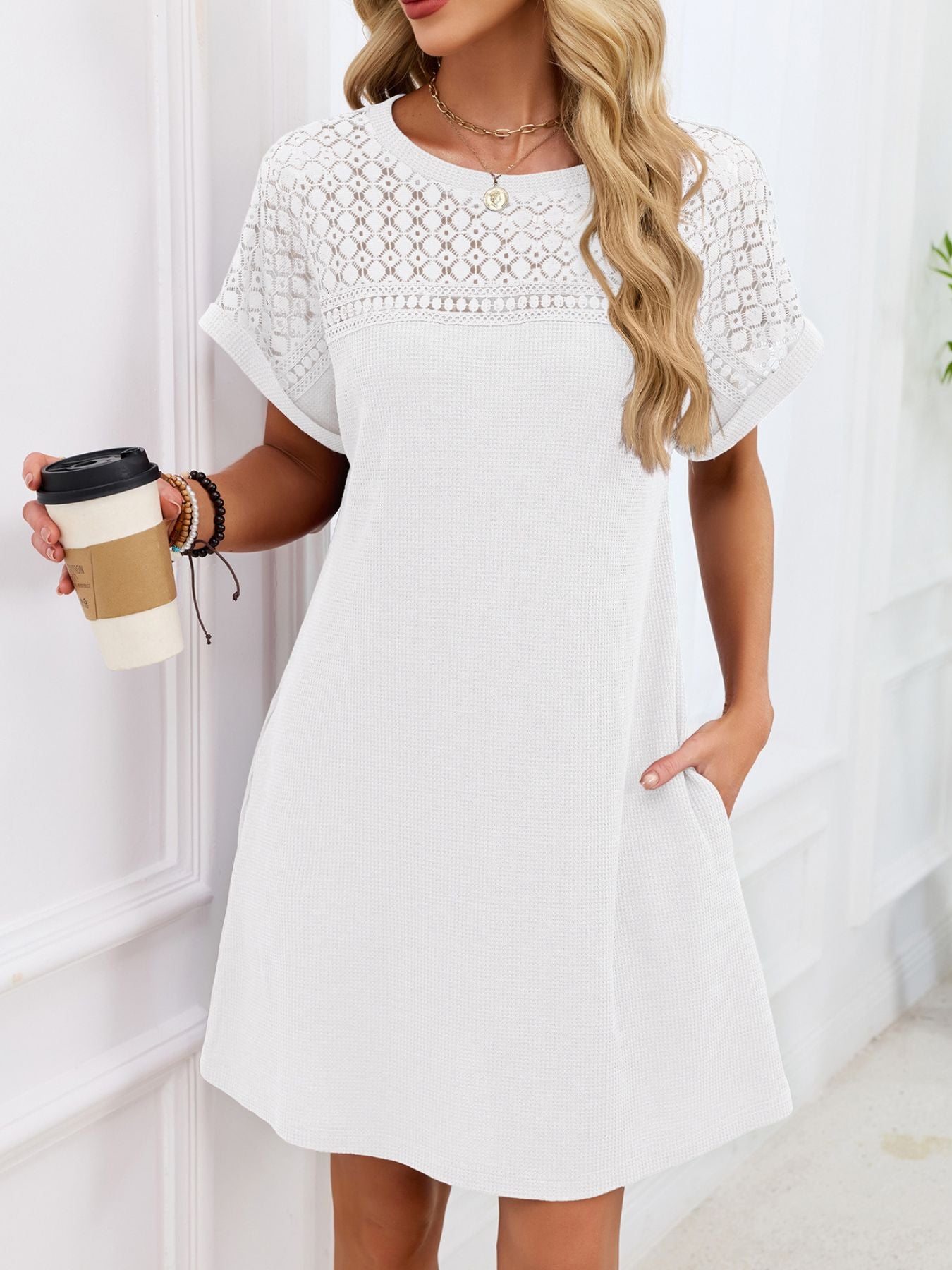 Woman wearing a white lace dress holding a coffee cup indoors.