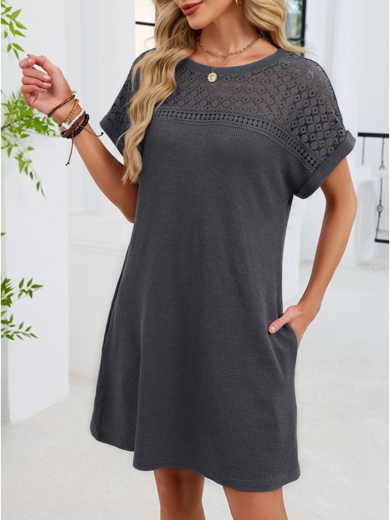 Woman wearing a gray dress with lace sleeves in an indoor setting.