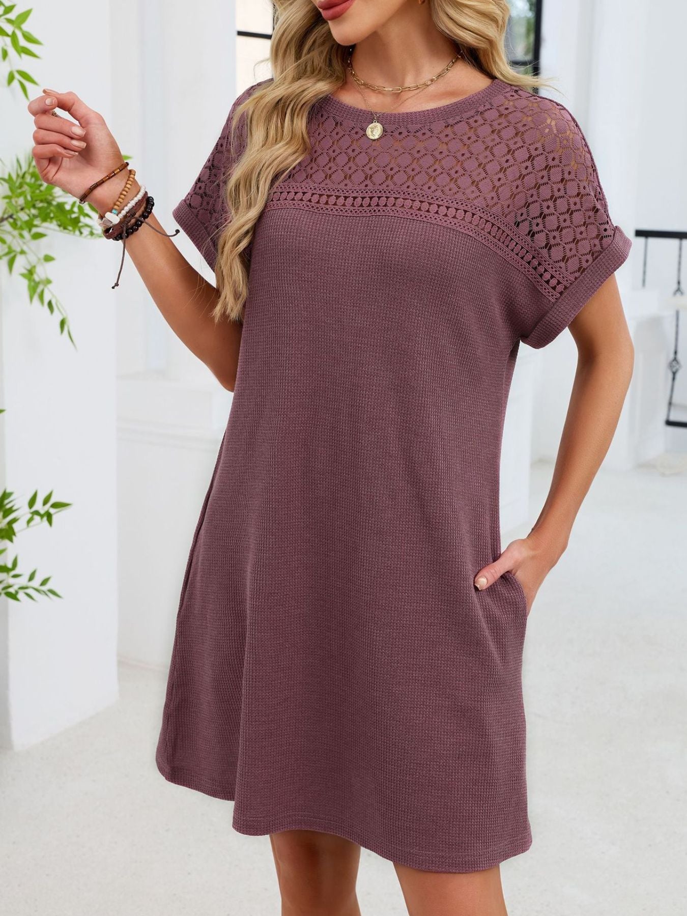 Woman wearing a purple dress with lace details on a white background