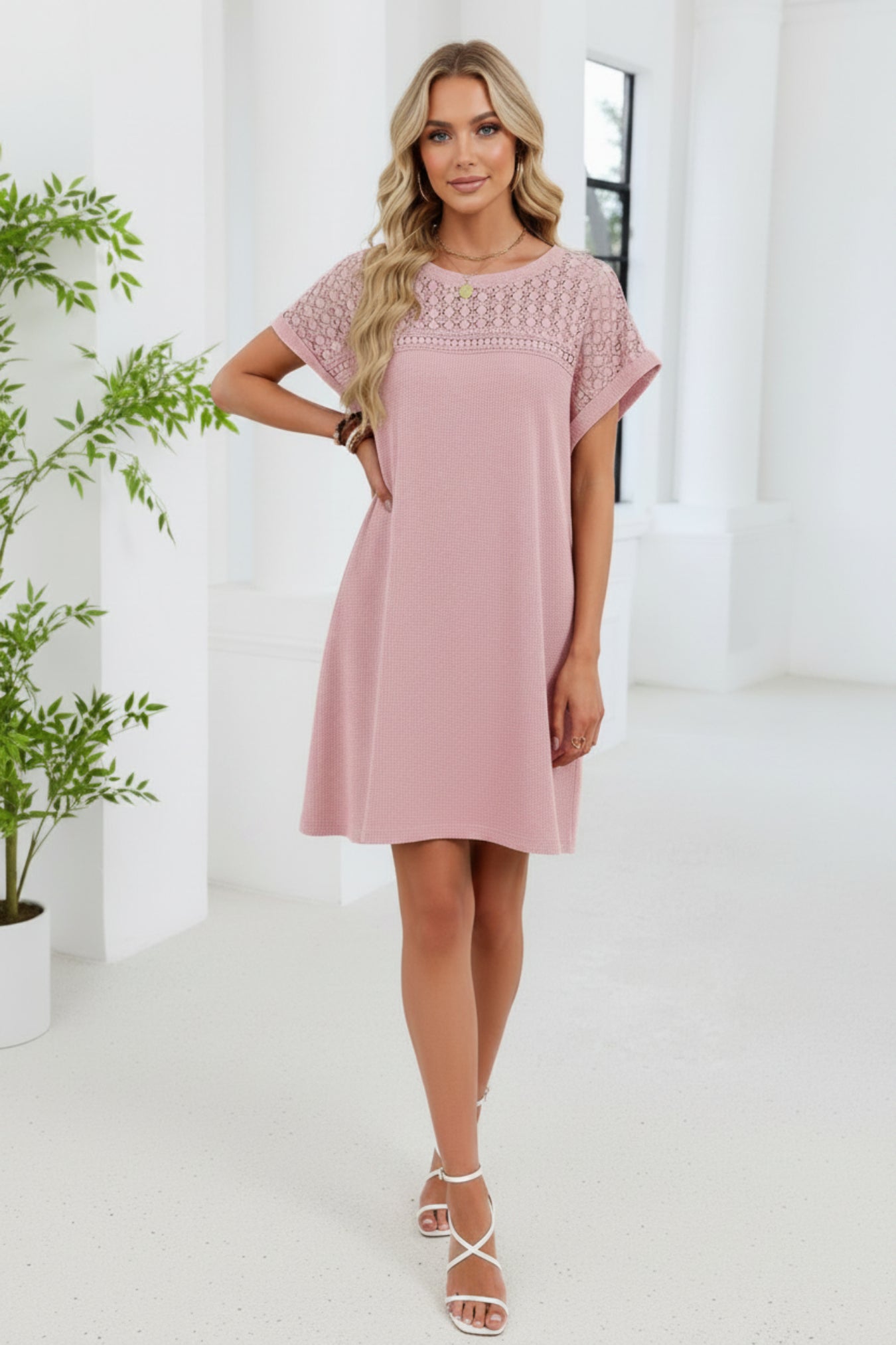 Woman wearing a pink dress with lace details in an indoor setting.