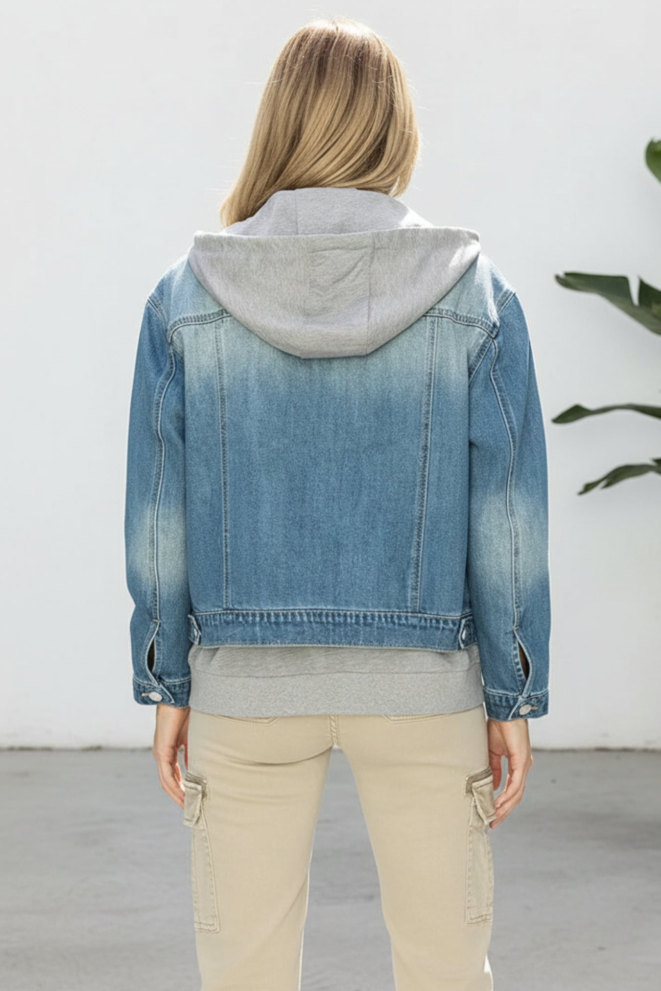 Denim jacket with a gray hood worn by a person on a white background
