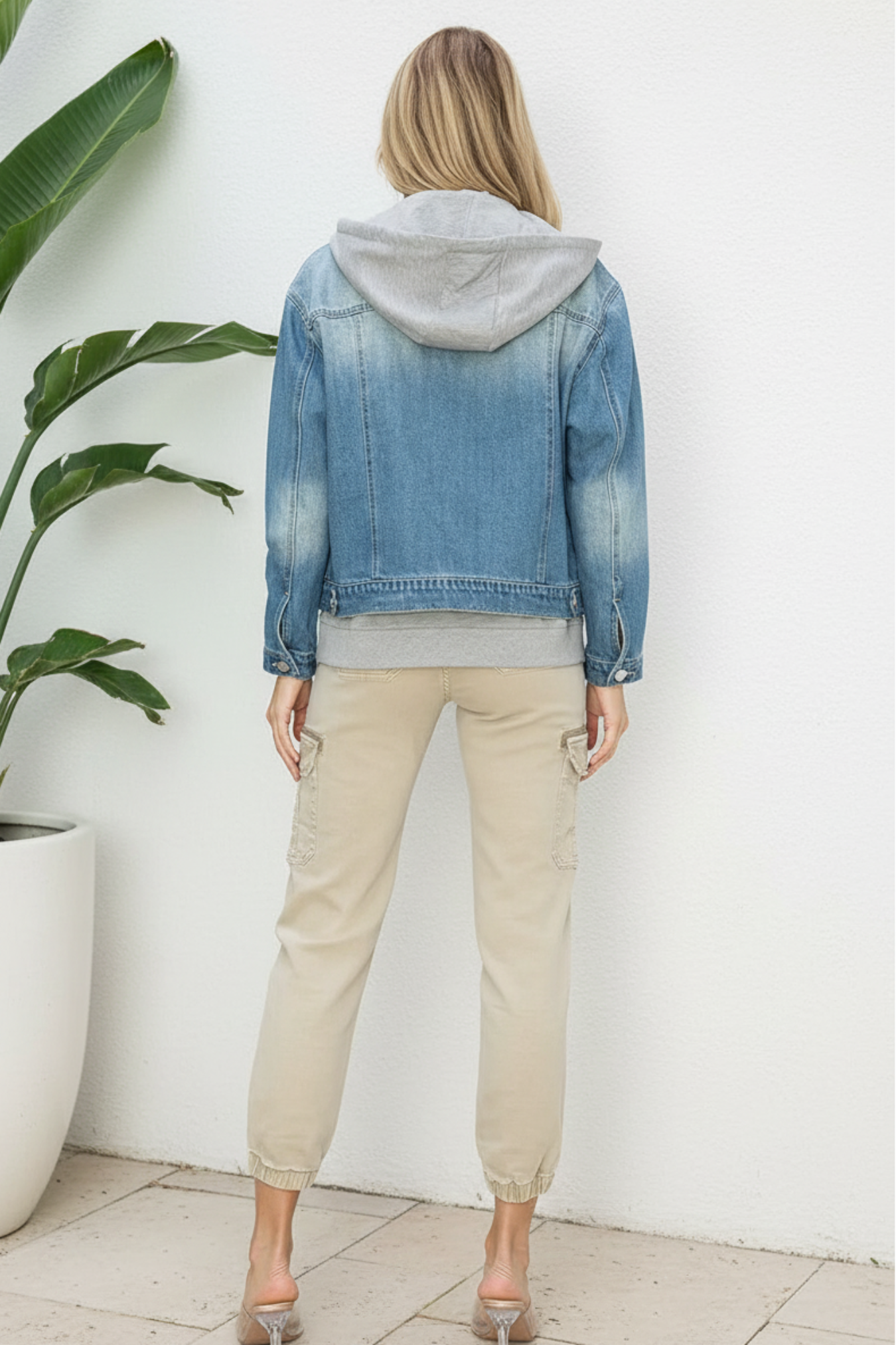 Person wearing a denim jacket and beige pants on a white background