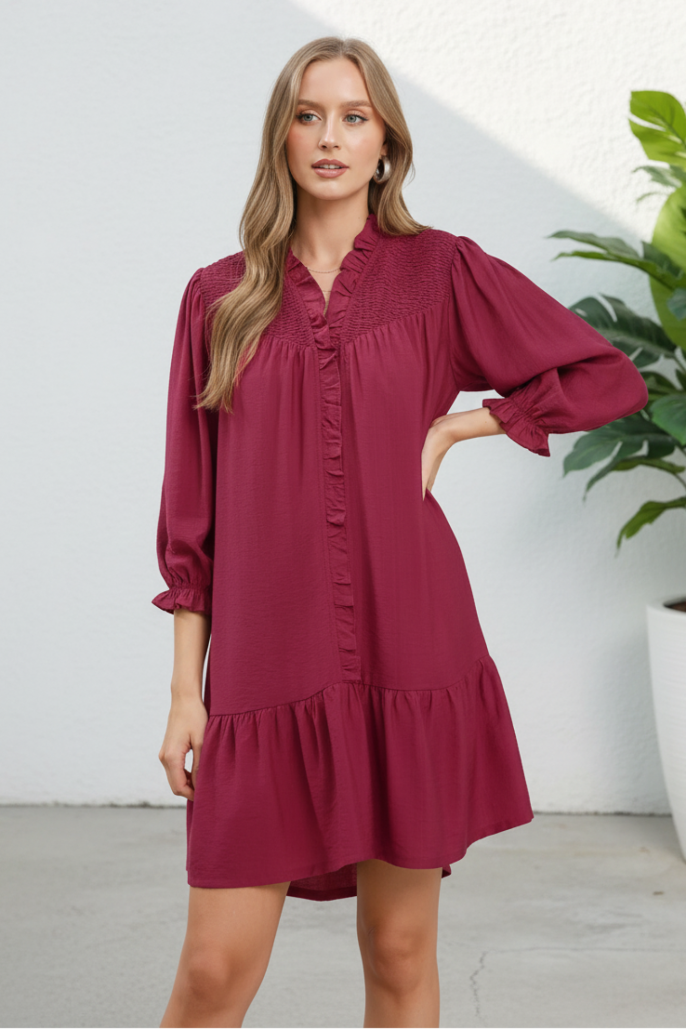 Woman wearing a burgundy dress with long sleeves on a white background