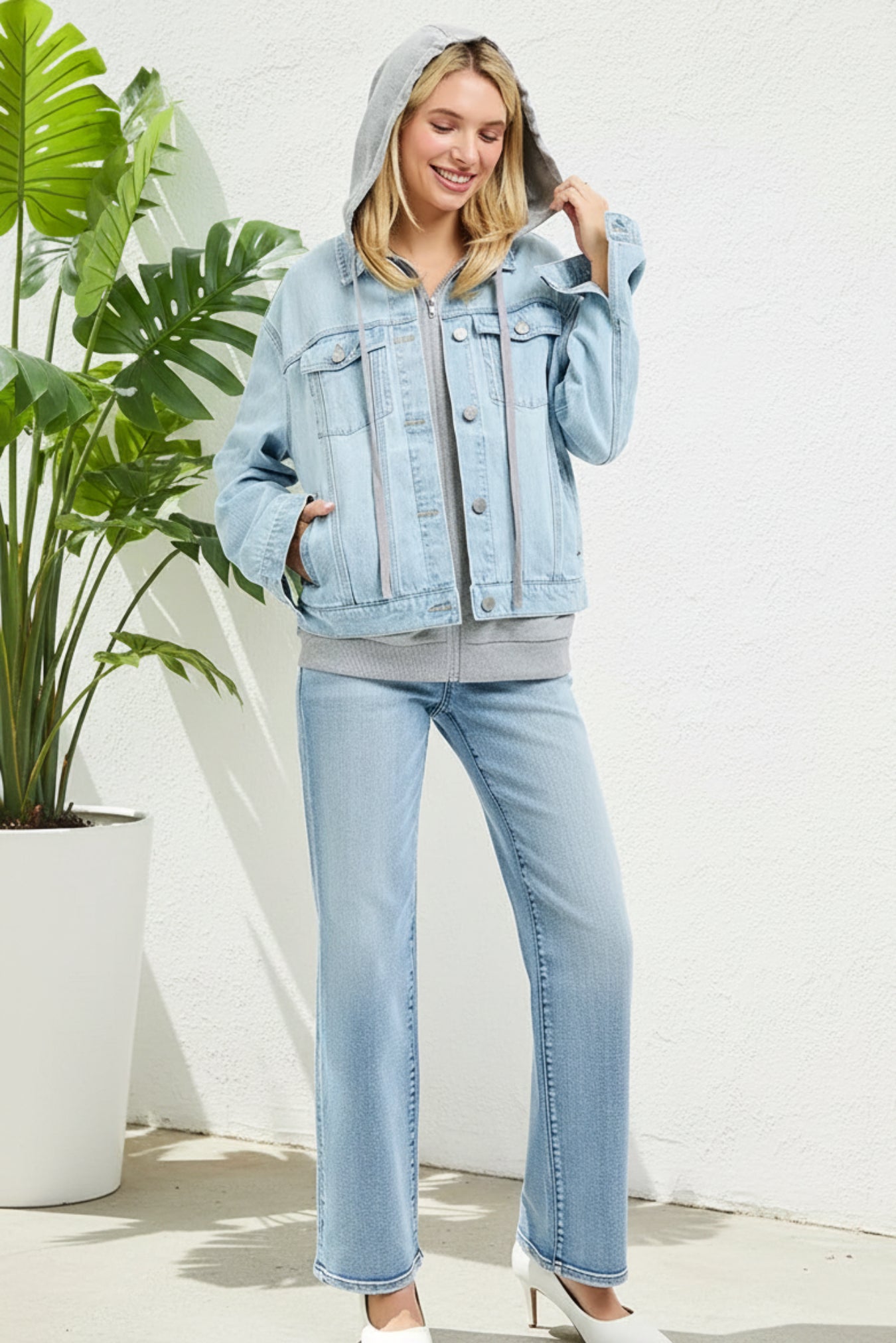 Woman wearing a light blue denim jacket and jeans on a white background