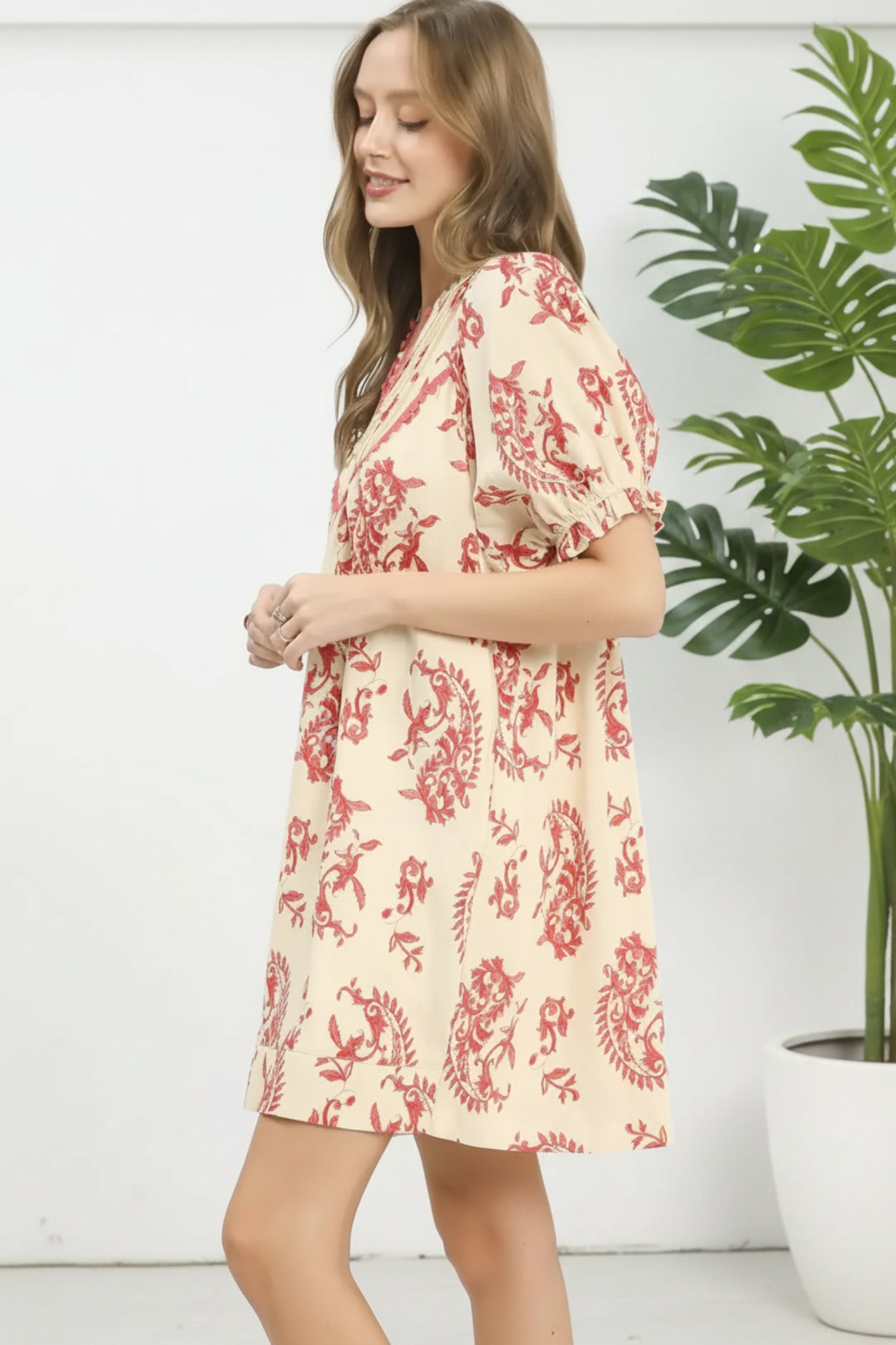 Woman wearing a red and white floral dress on a white background