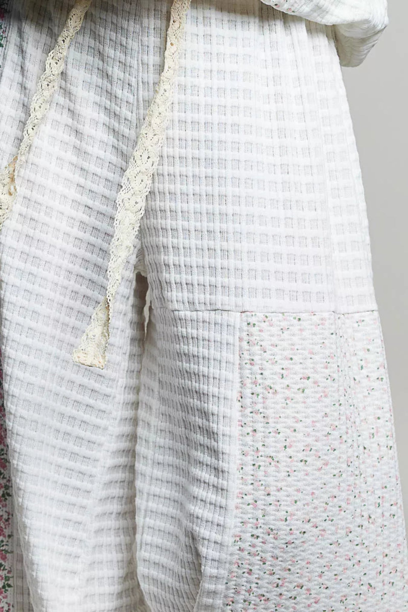 Close-up of a textured fabric with a checkered pattern and lace trim on a plain background