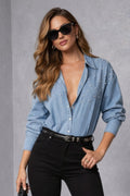 Woman wearing a blue shirt and black pants against a gray background