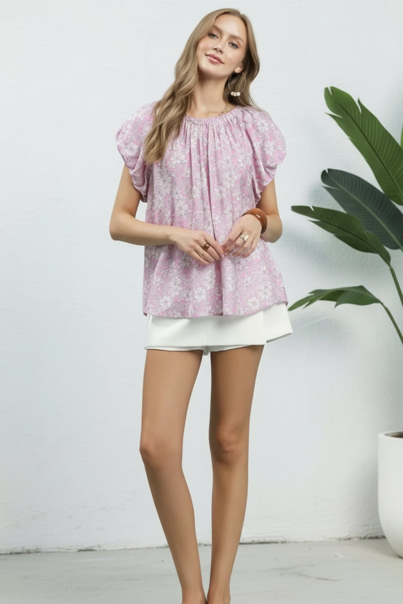 Woman wearing a pink floral blouse and white skirt on a white background