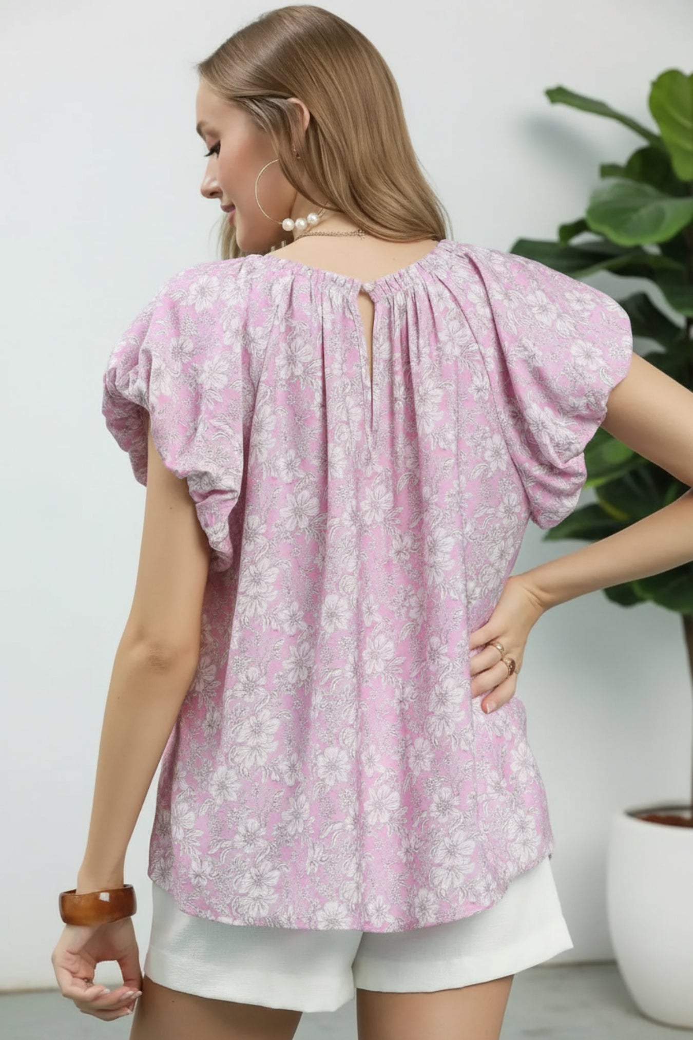 Woman wearing a pink floral blouse against a white background