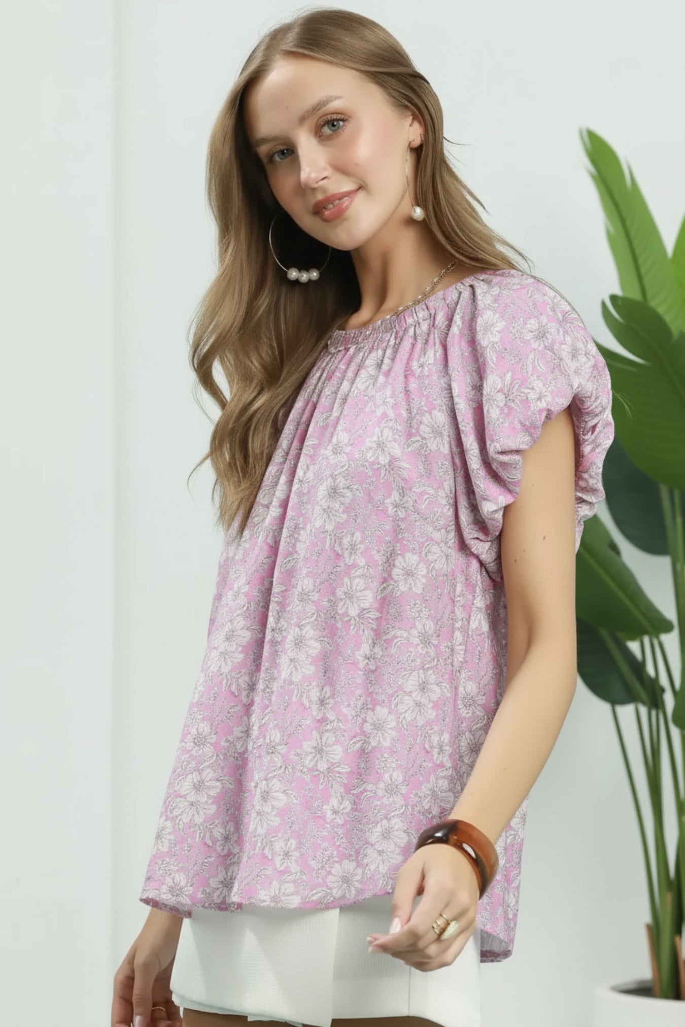 Woman wearing a pink floral blouse against a white background