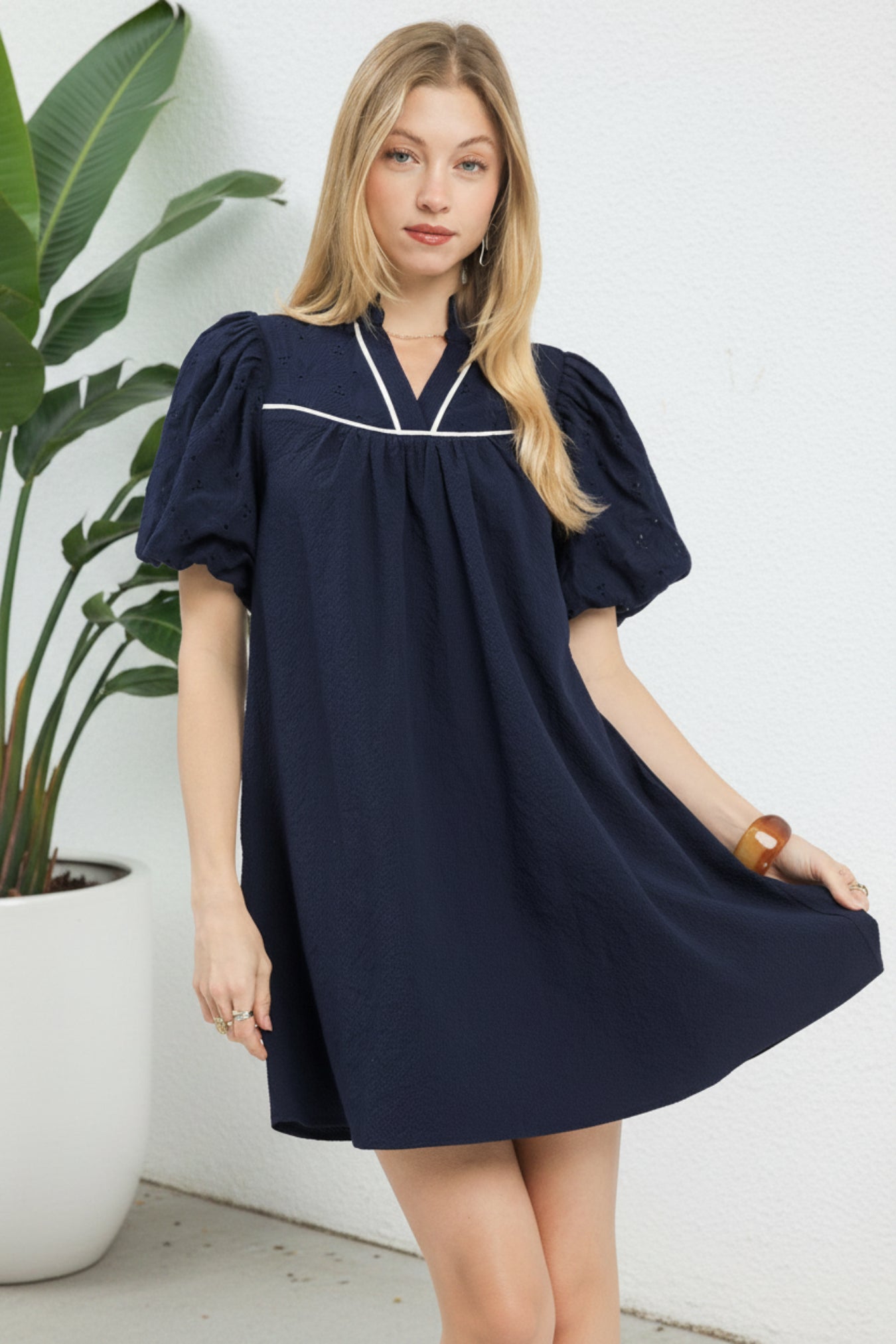 Woman wearing a navy dress with white trim on a white background