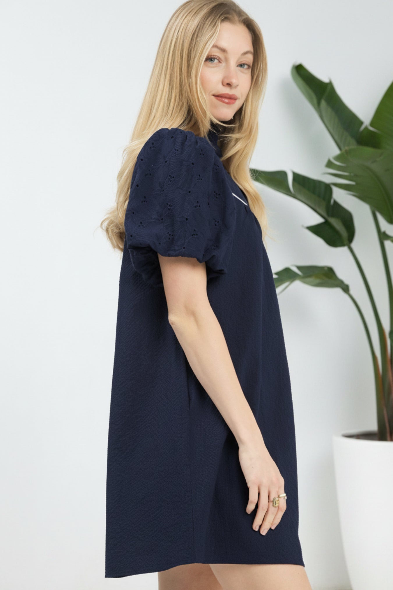 Woman wearing a navy blue dress with puff sleeves on a white background