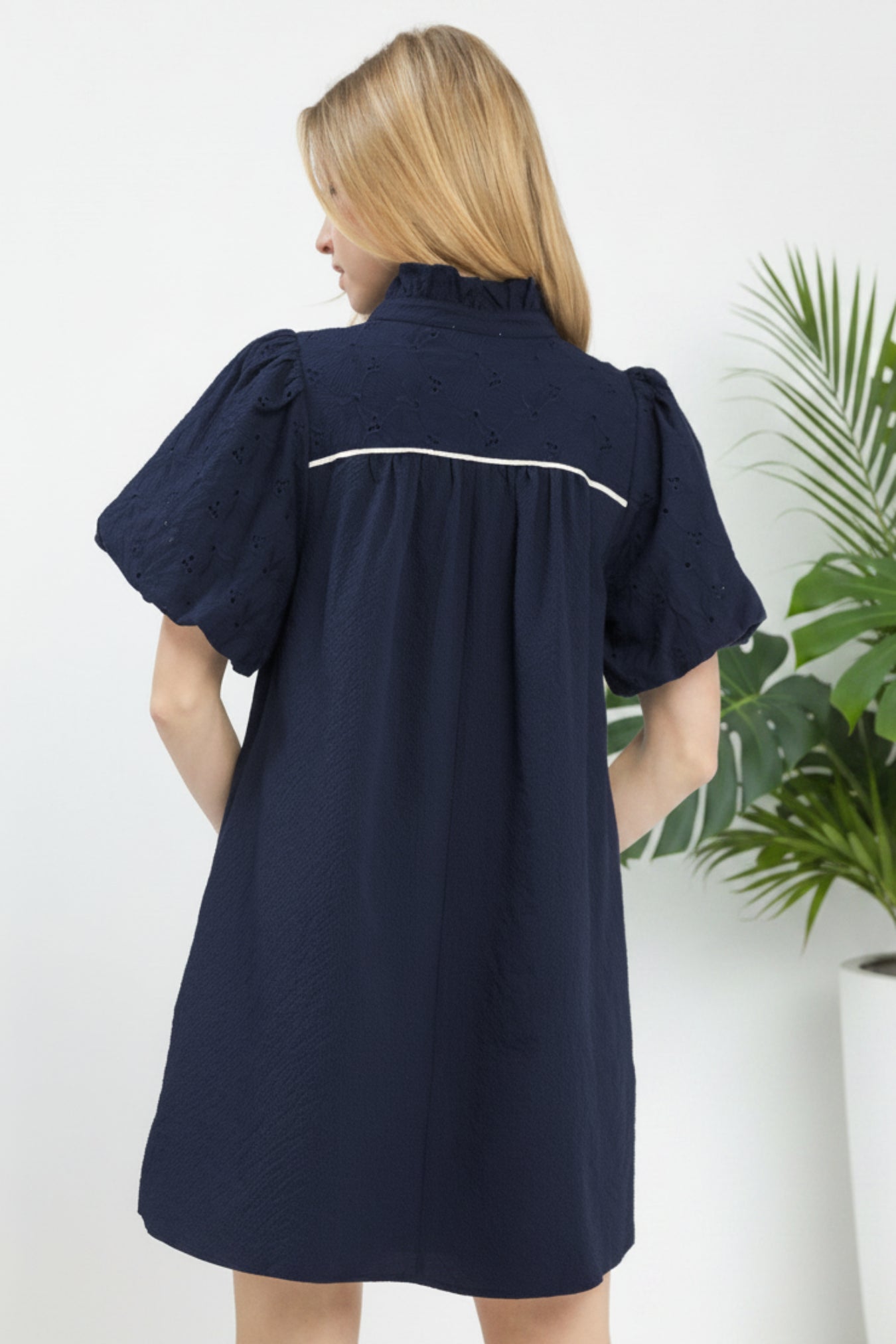 Woman wearing a navy dress with white trim on a white background