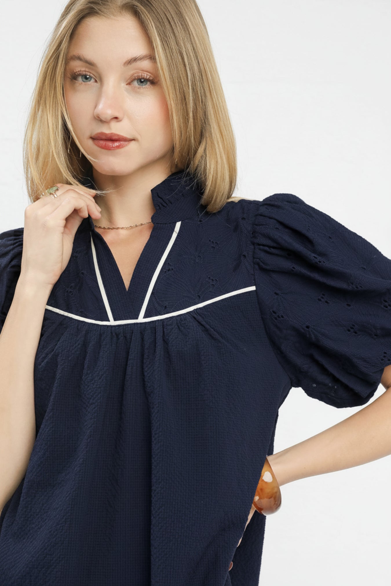 Woman wearing a navy blue dress with white trim on a white background