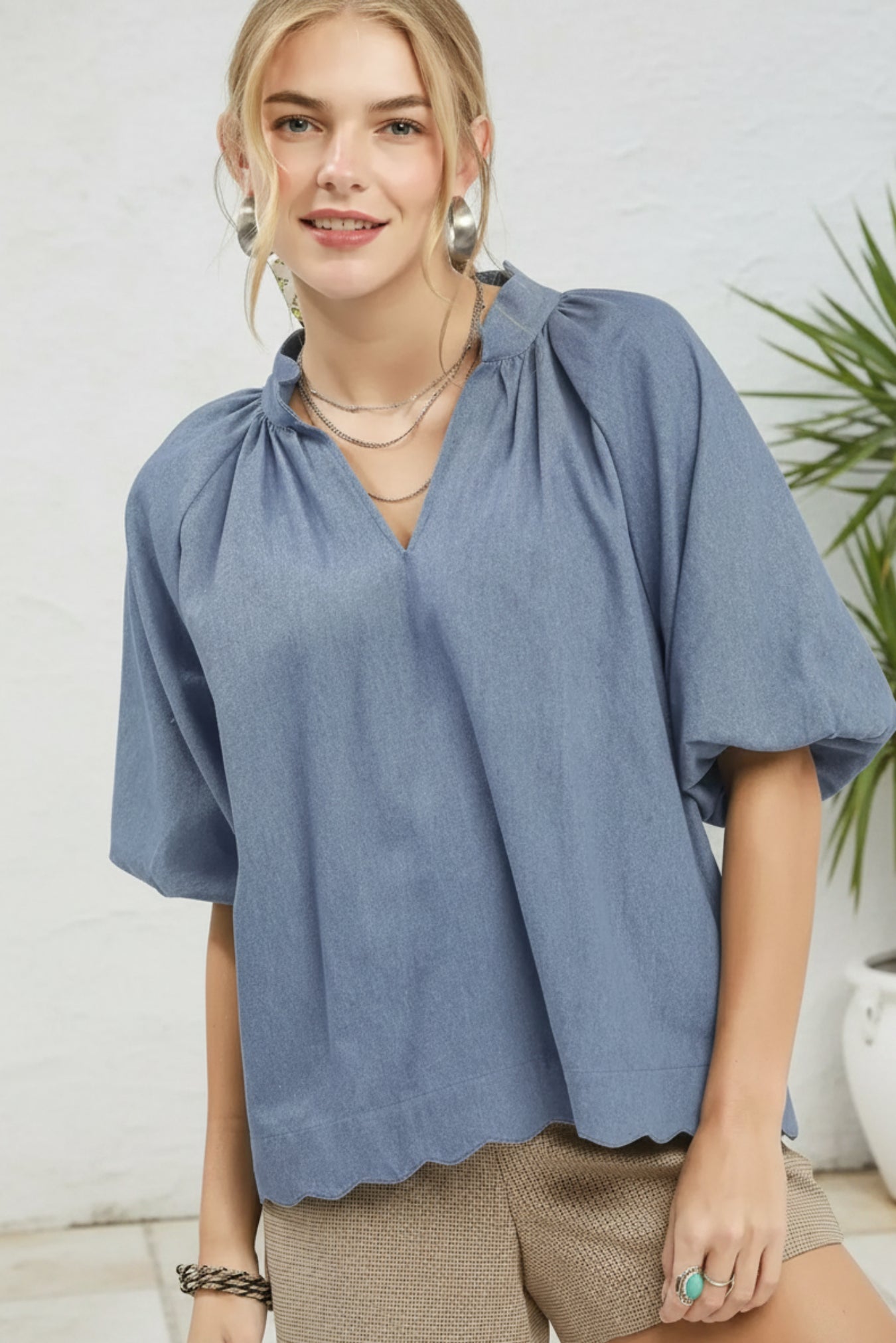 Woman wearing a blue blouse and beige shorts on a white background