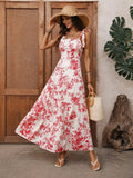 Woman in a floral dress and sun hat standing in front of wooden doors with a plant in the background.