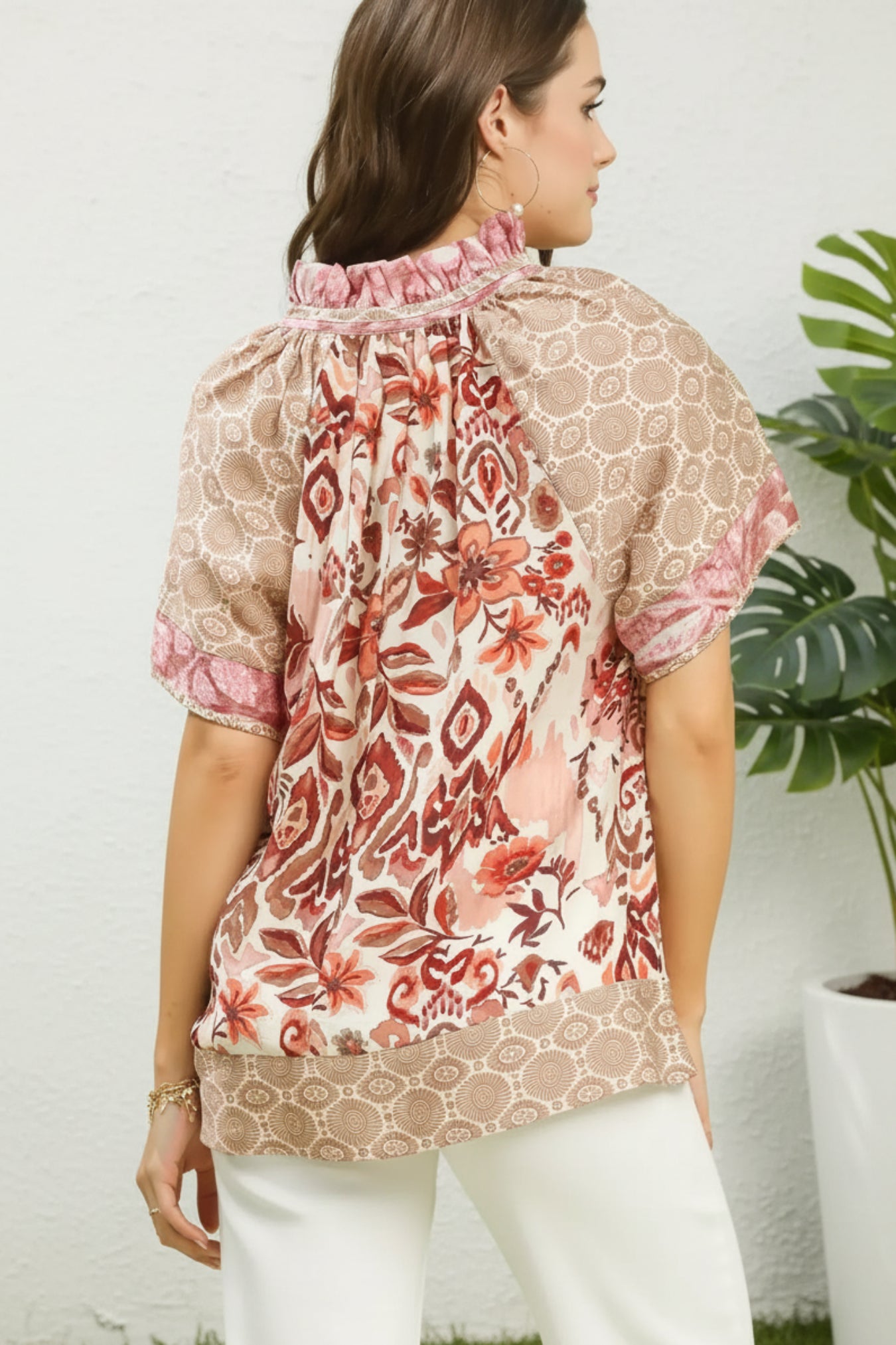 Woman wearing a patterned blouse with a rose mix design on a white background