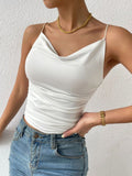 Person wearing a white tank top and blue jeans against a plain background