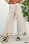 Beige pleated pants worn by a person on a white background